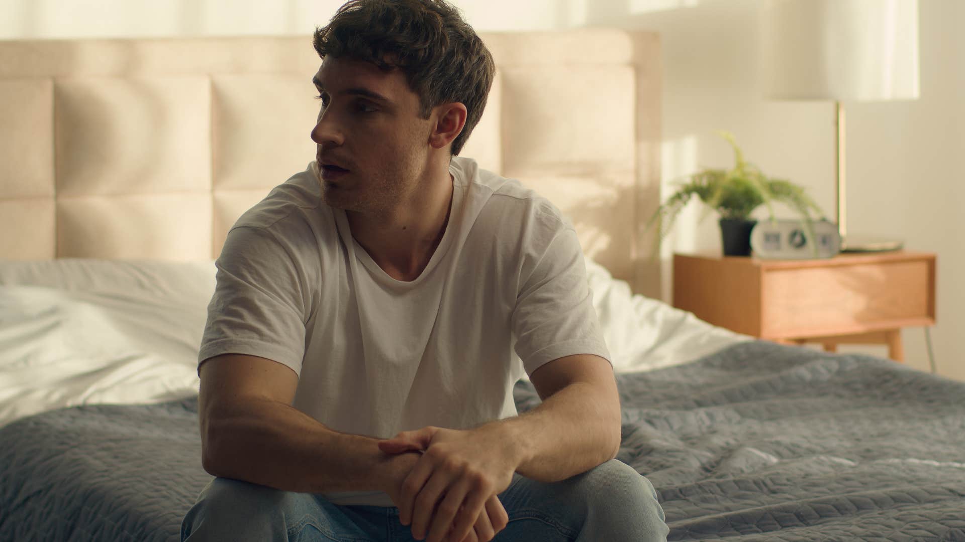 ashamed man sitting in bed avoiding quality time with his partner