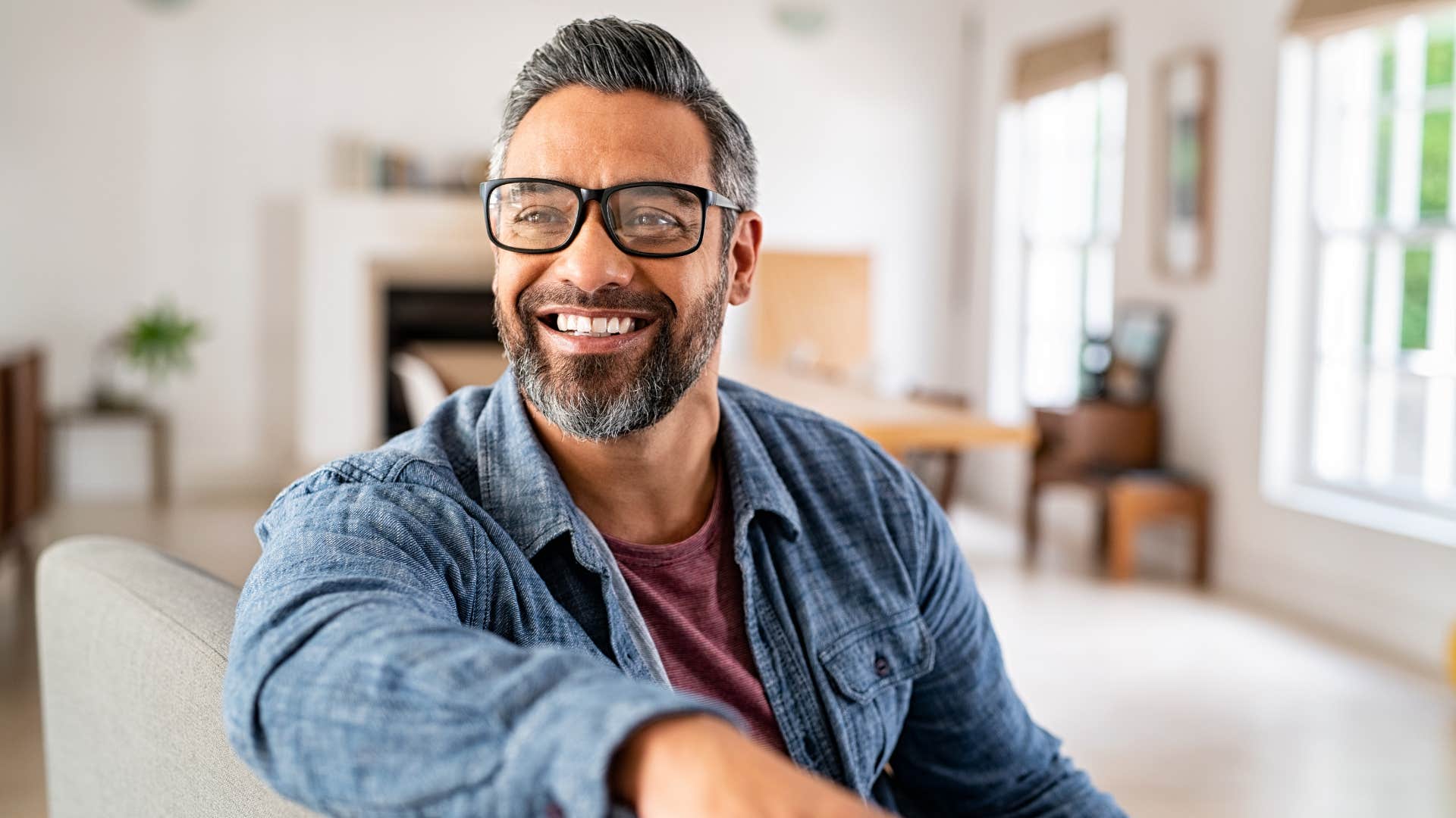 man smiling sitting on couch saying no without guilt
