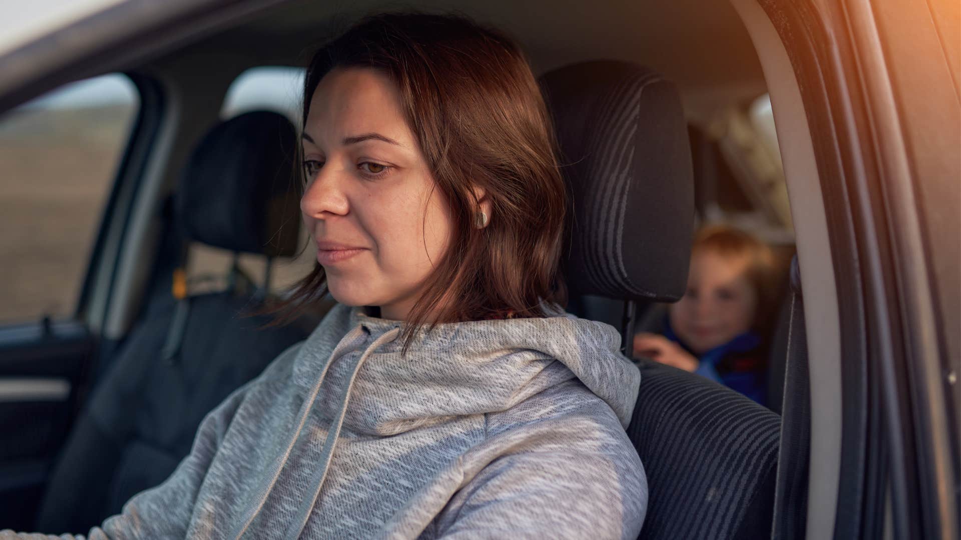 woman sitting in car with expectations for her kids to do it all