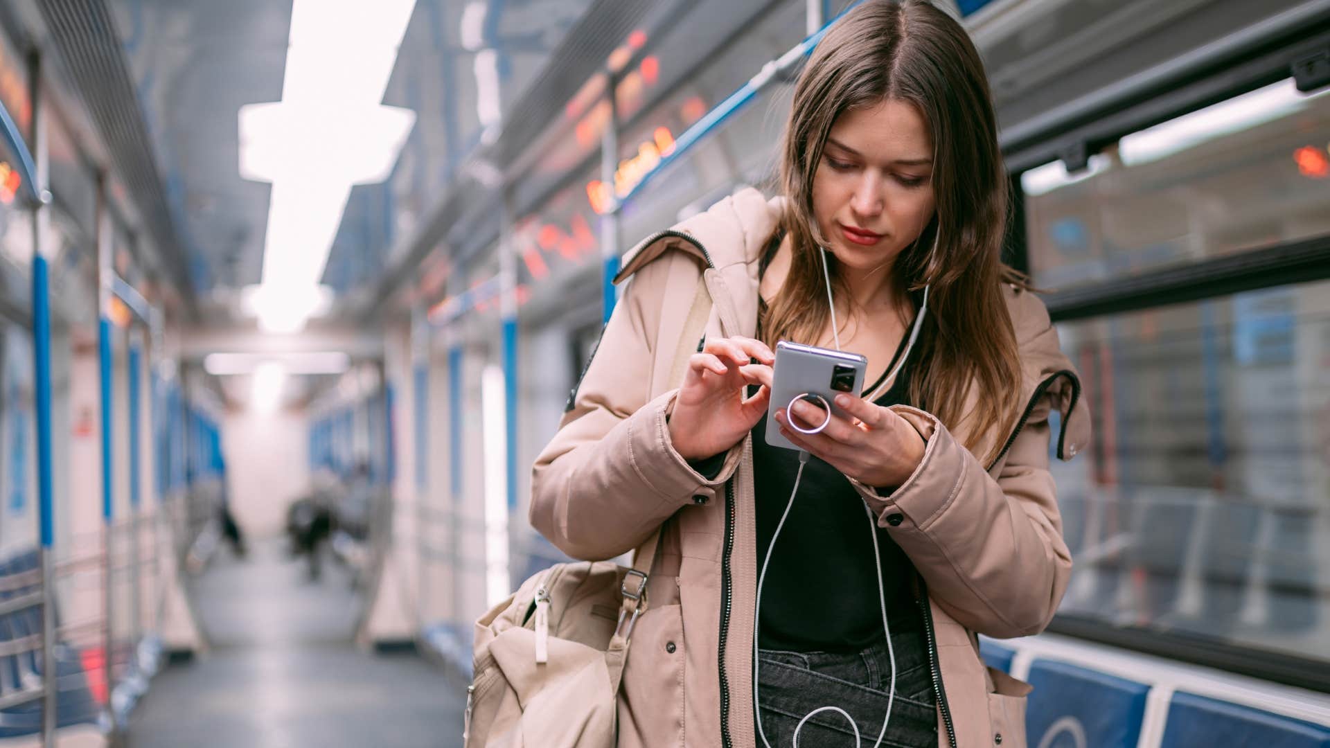 woman who needs to be available 24/7 looking at her phone on the train