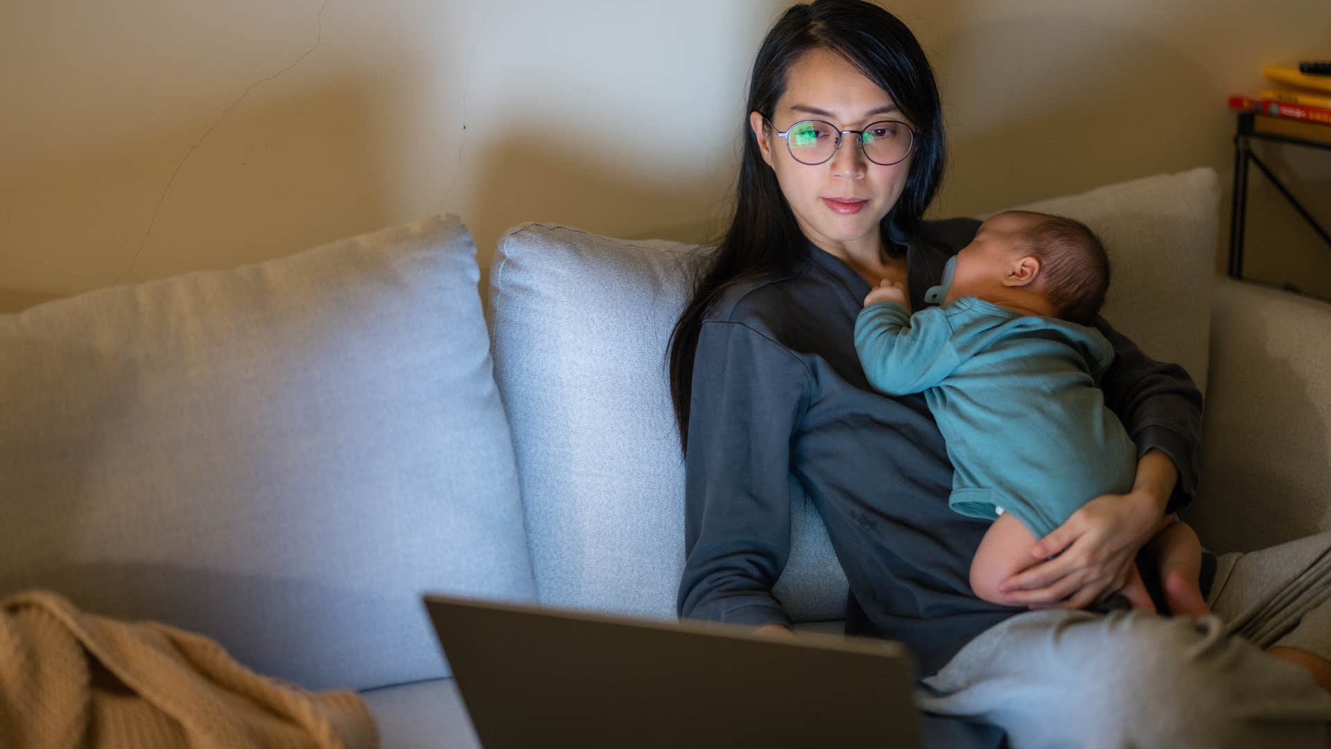 stressed millennial mom looking for a second job to survive while holding baby
