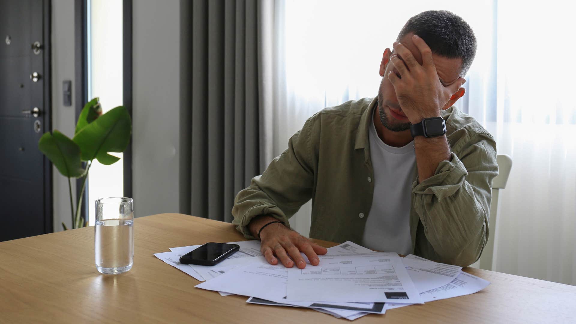 millennial man stressed and struggling with homeownership doing bills