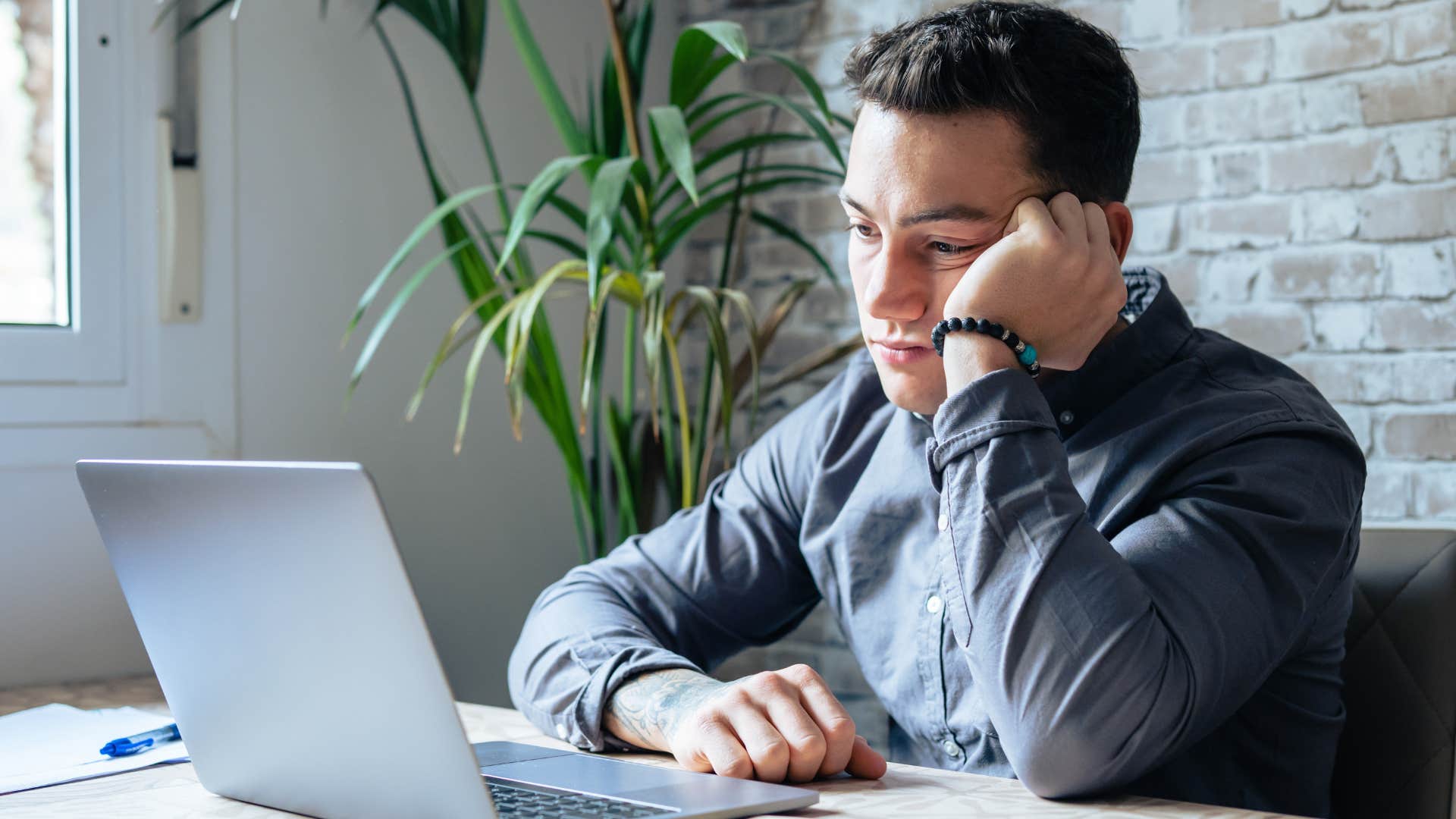 millennial man thinking about the unmet promises of adulthood while working