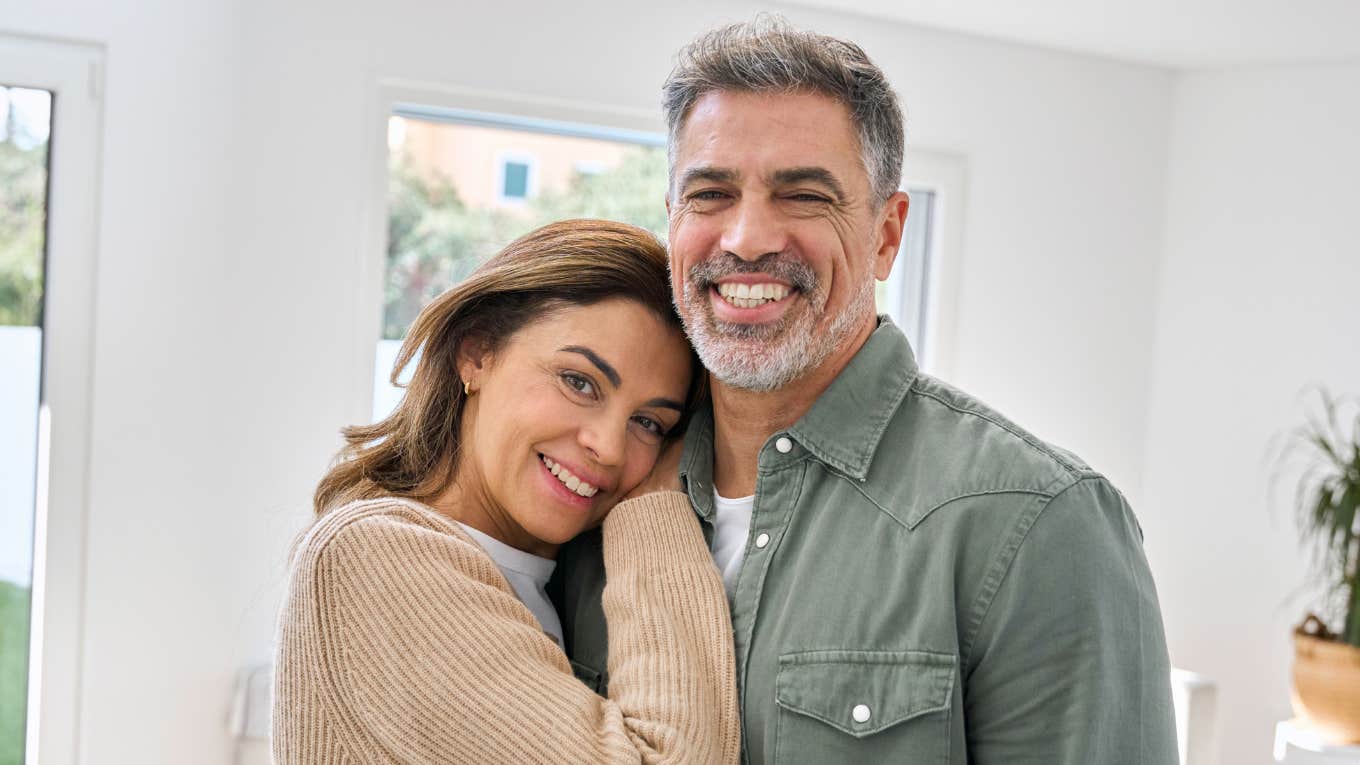 middle aged couple smiling hugging each other at home