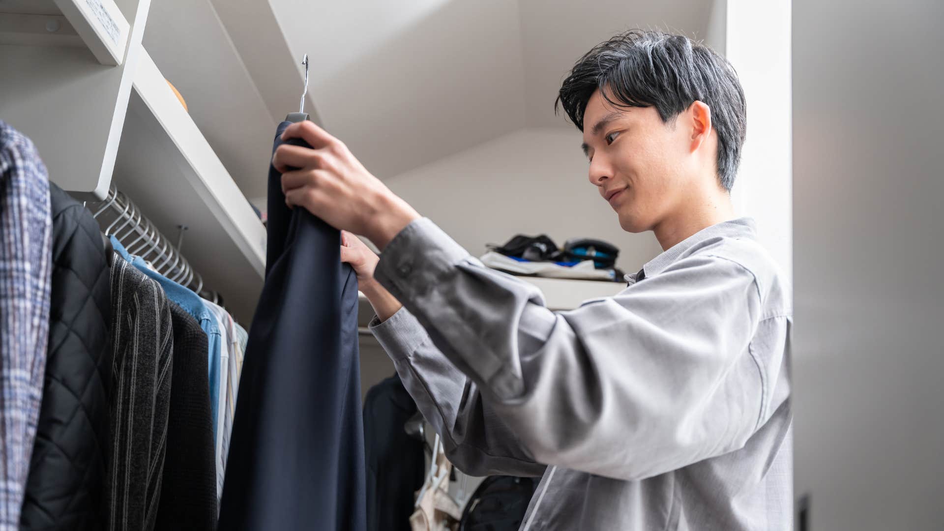 wealthy man looking at clothes in his closet that still have price tags on
