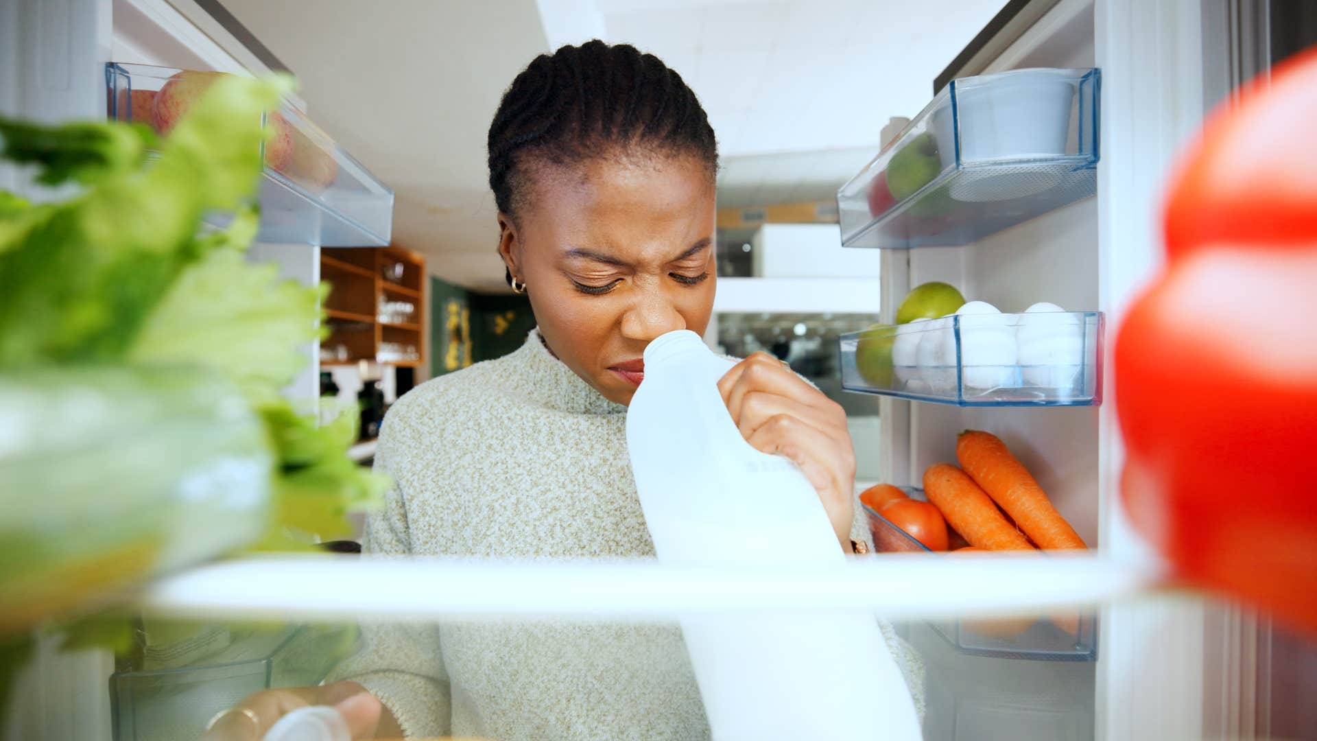 woman smelling expired food in moms fridge