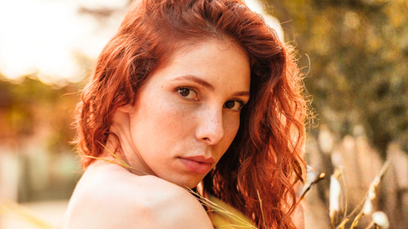 Close-up of red-haired woman looking back intensely, reflecting the emotional grip of obsessive love that studies say can secretly sabotage success and happiness.