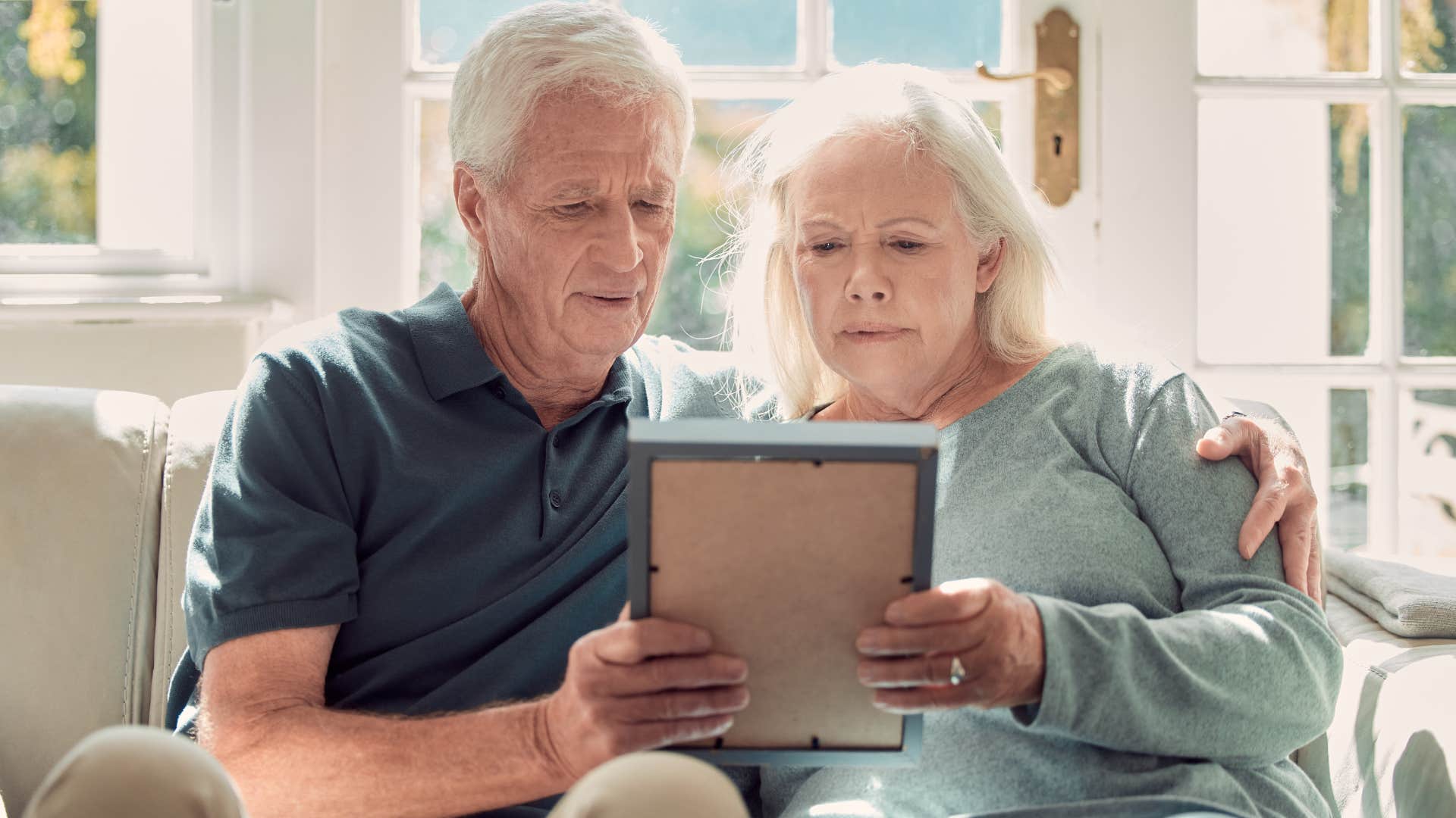 older couple looking at photo thinking about their kids' milestones