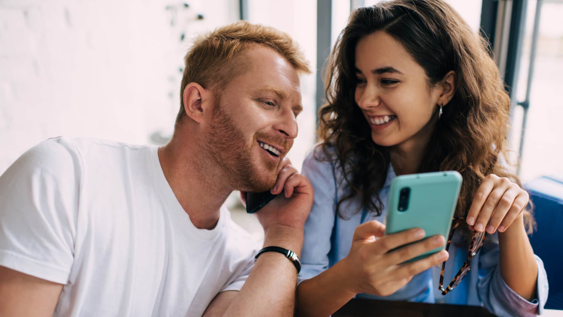 man saying you're hilarious to woman showing him phone