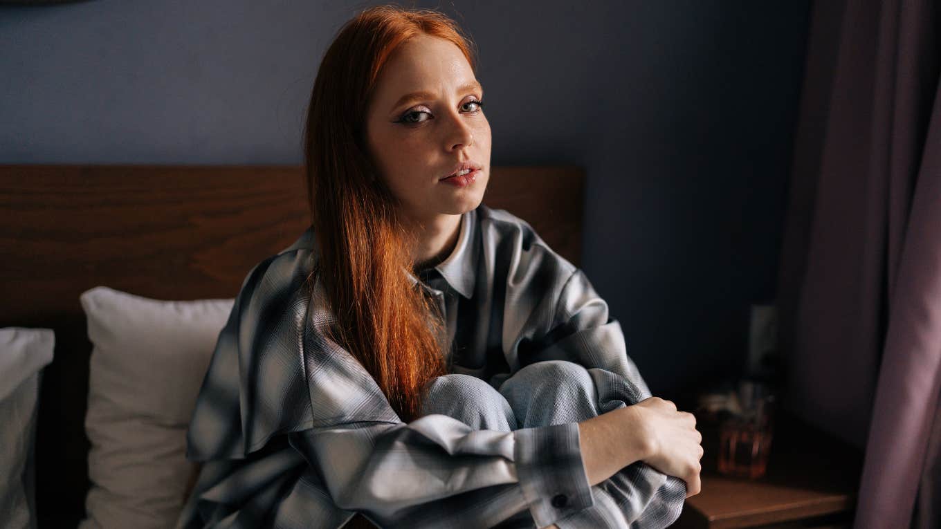 stressed serious young woman sitting in bed