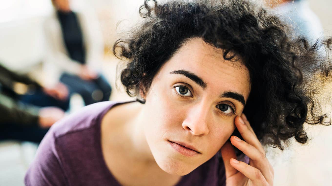 Stressed woman looking tense, capturing the emotional weight of people who can’t fully relax around their parents due to unresolved wounds.