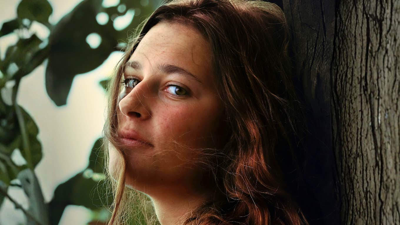 Uneasy emotionally unstable woman peering over her shoulder showing early signs people notice in unstable relationships./