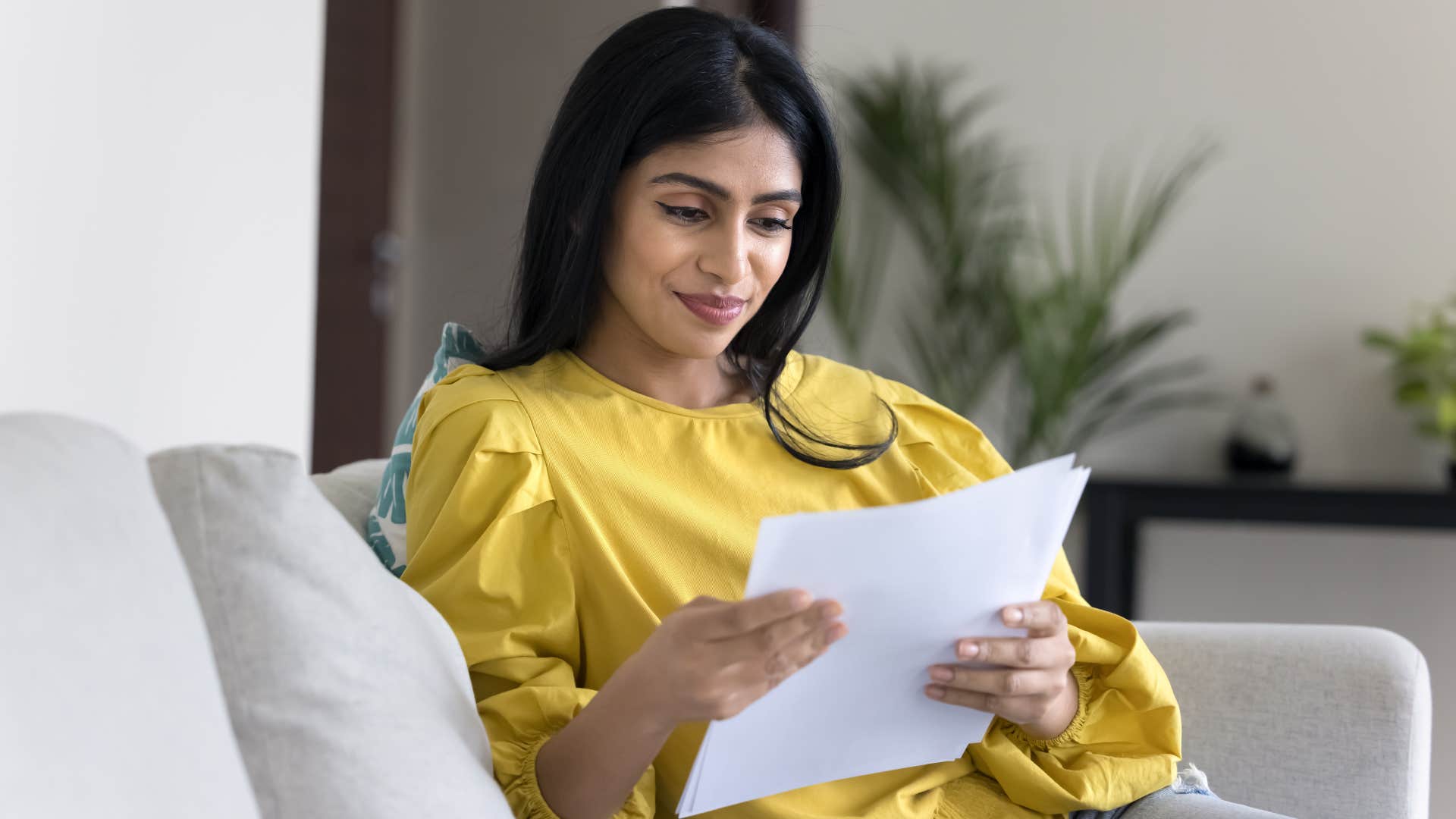 woman reading a letter from loved ones on couch