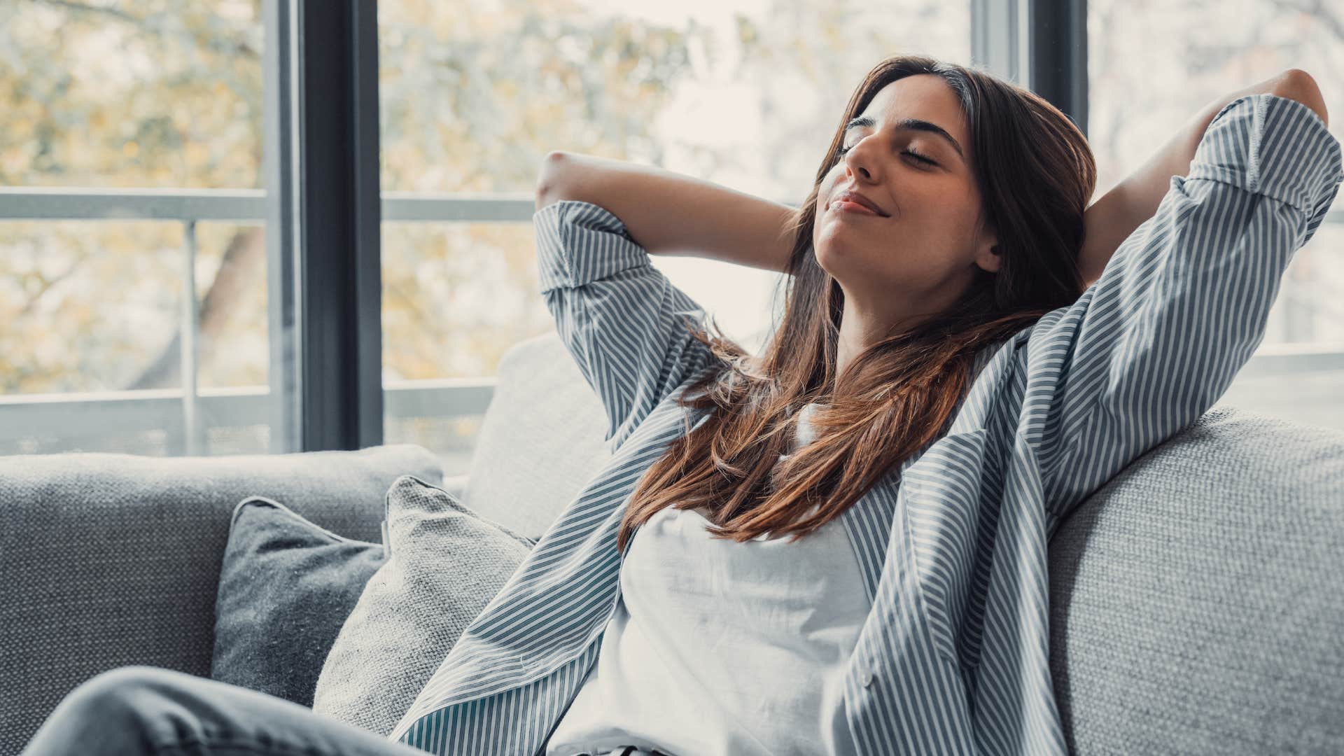 woman laying back and relaxing on couch prioritizing peace over perfection
