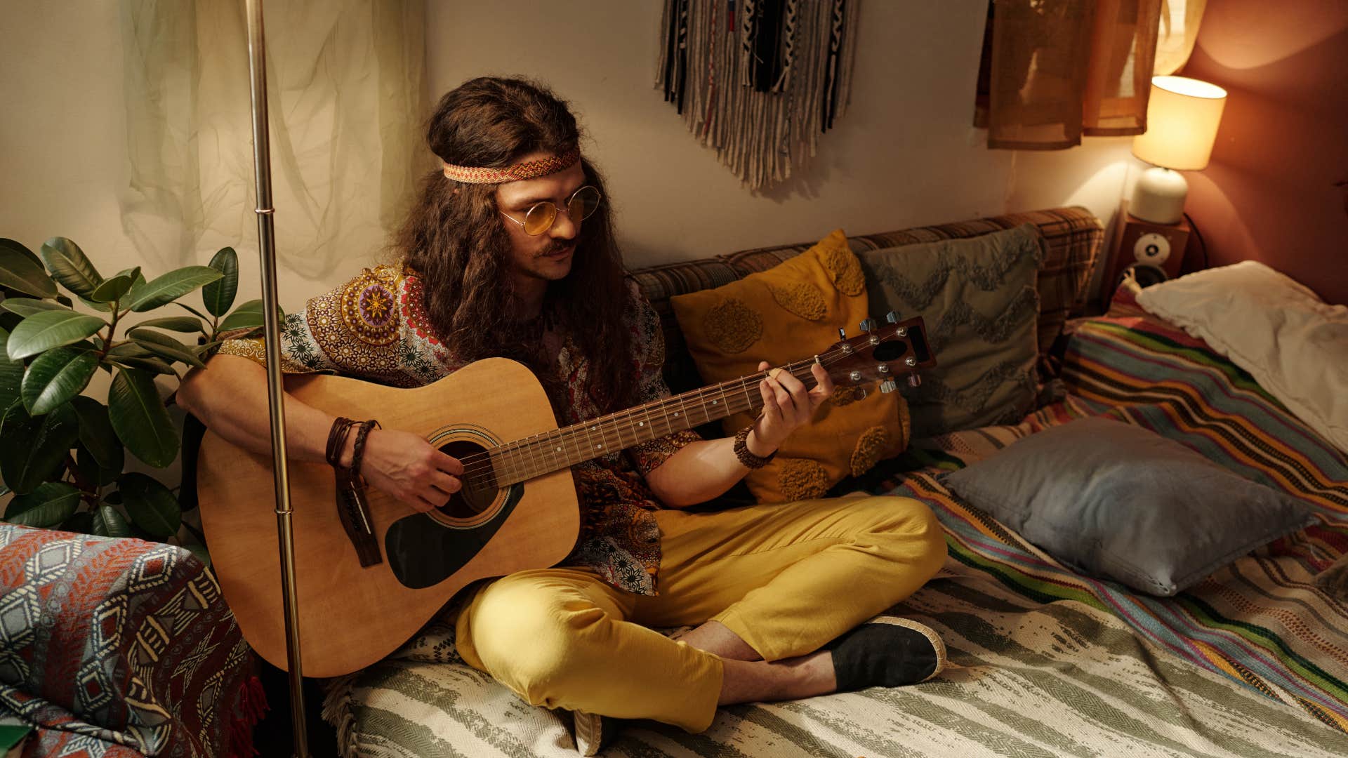 man playing the guitar on couch