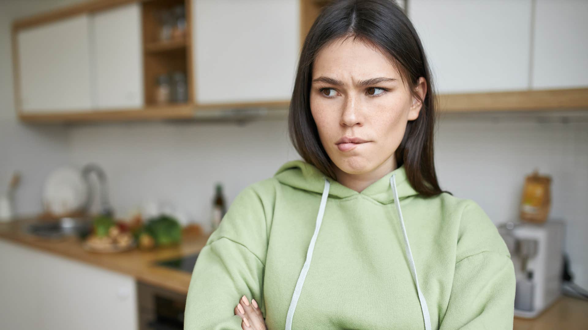 woman in green shirt looking upset as she crosses arms and has an all or nothing mentality