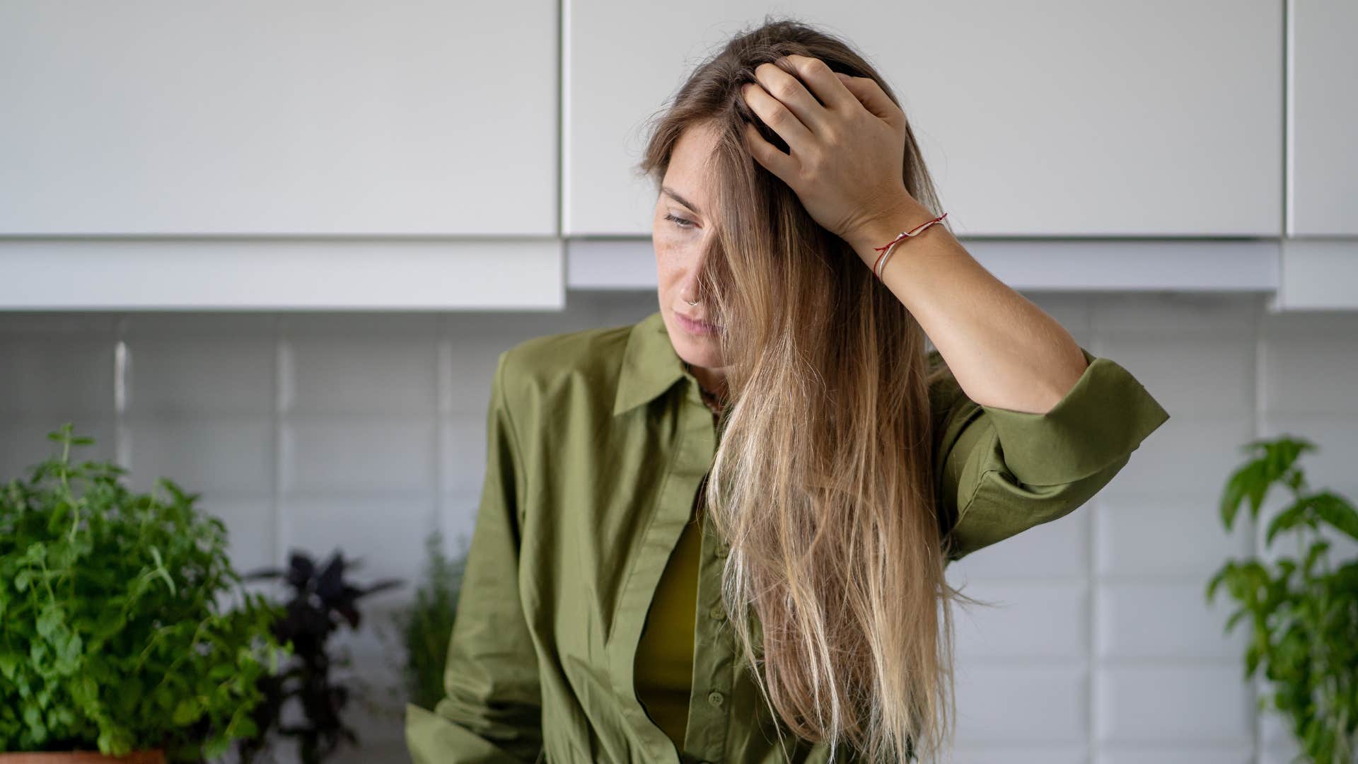 woman in green shirt dealing with decision fatigue as she rubs her head 