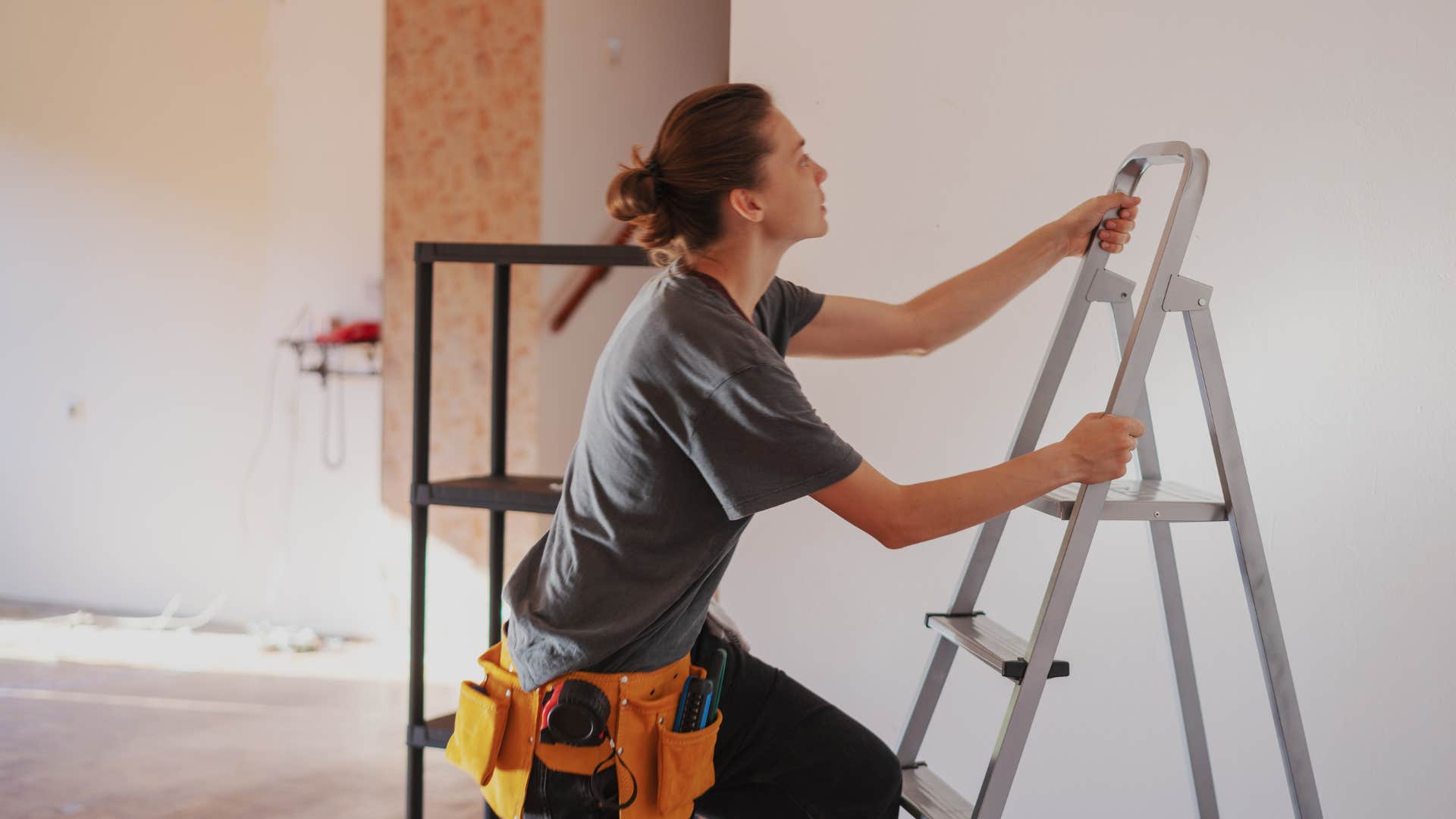 woman in gray shirt climbing ladder as she has a fear of height