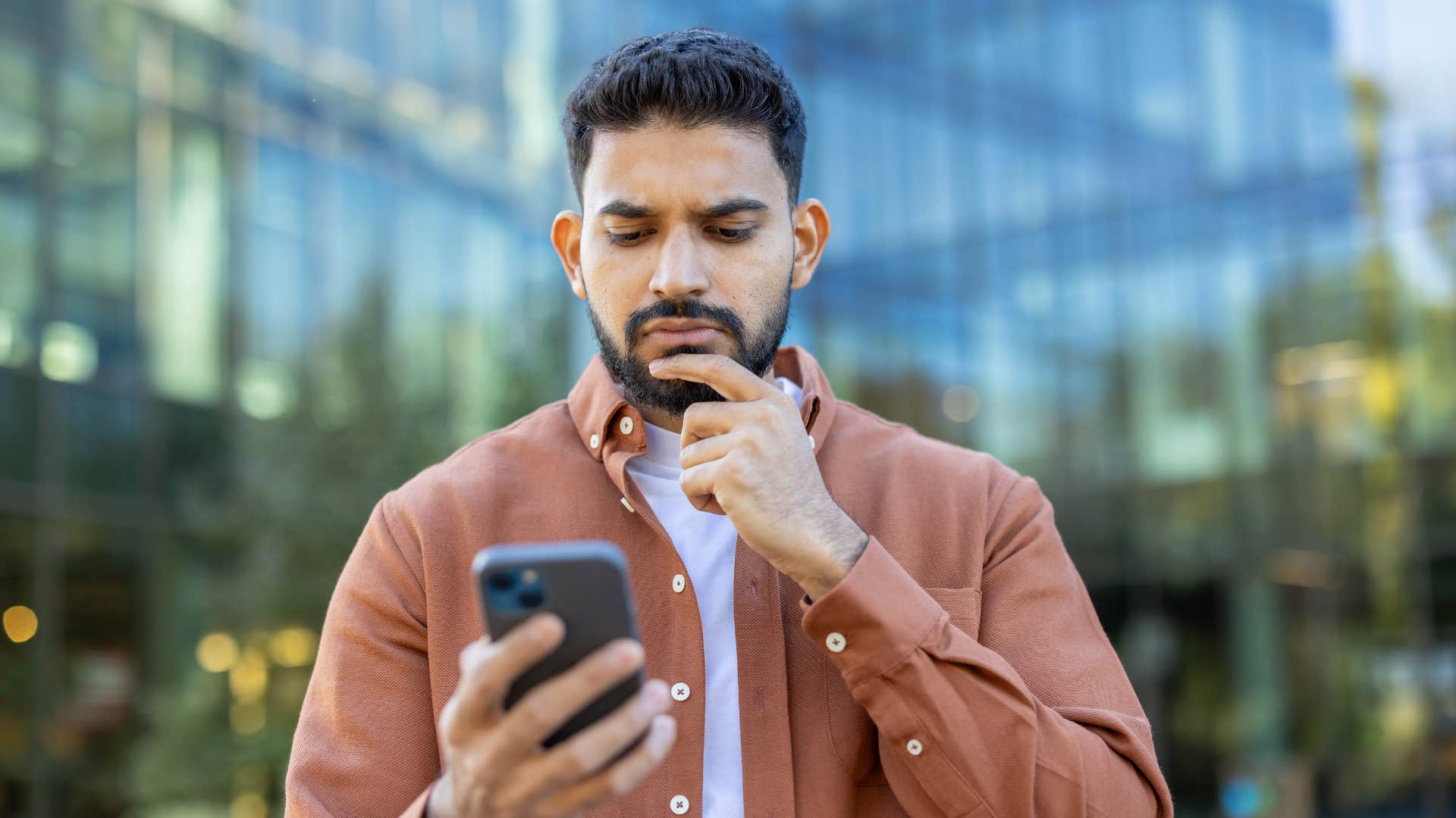 man staring at phone as he has forgetfulness due to overload