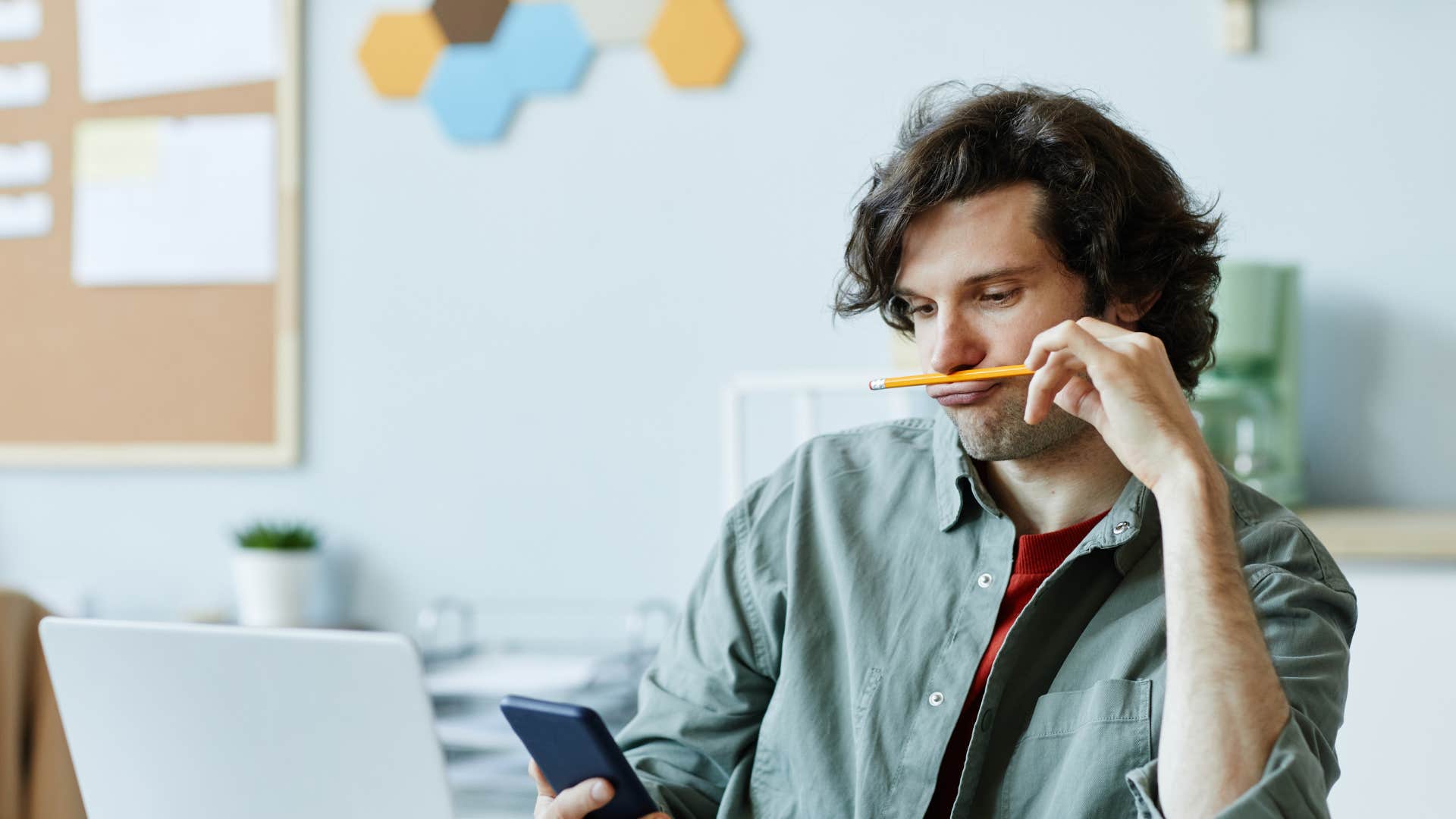 man looking at laptop and joking around with pencil as he struggles with adhd