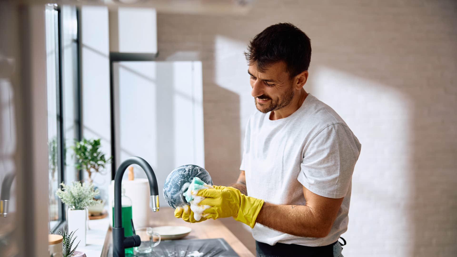man cleaning dishes because stillness feels uncomfortable