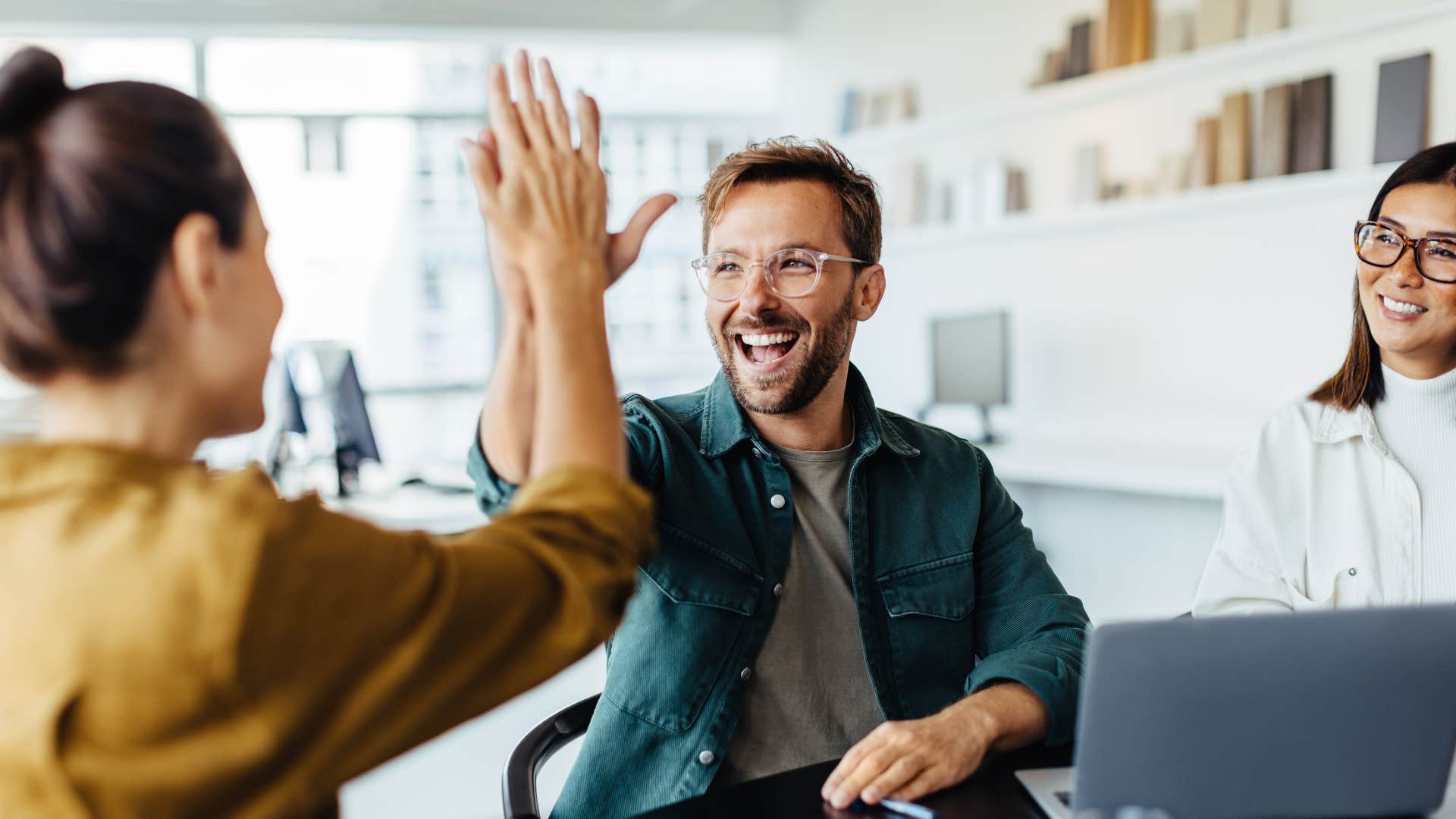 man in green jacket high fiving woman as he prefers subtle affection