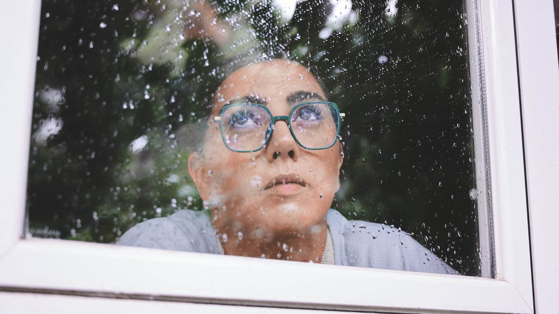 Woman who appreciates introspection sitting inside on a rainy day.