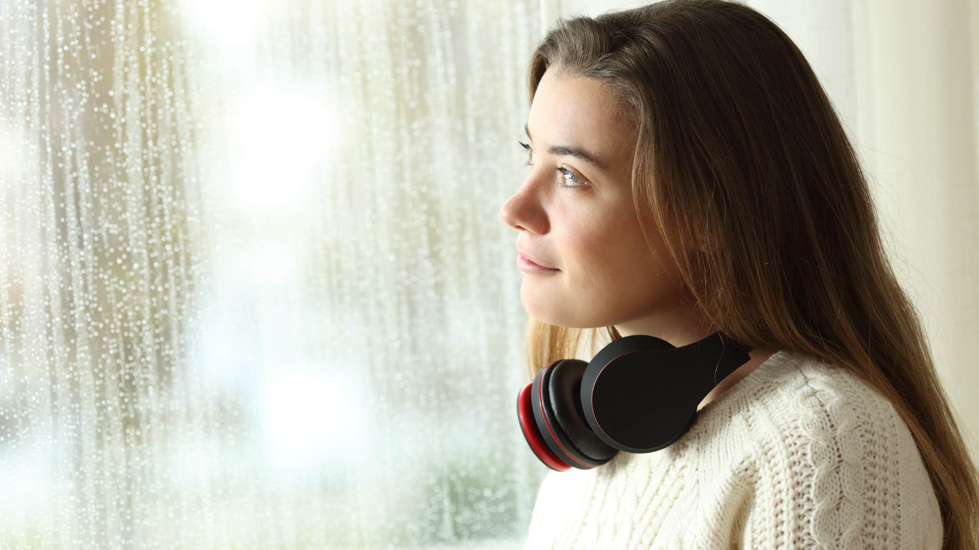 Woman who's in touch with their senses looking out a window.