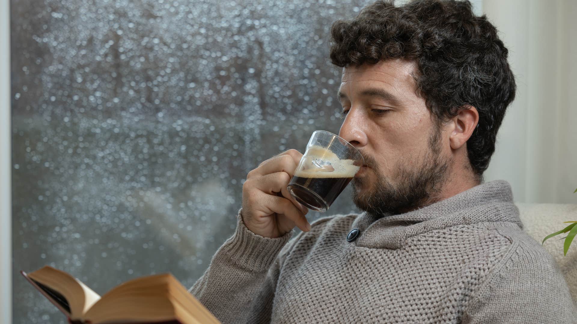 Romantic man reading at home on a rainy day.