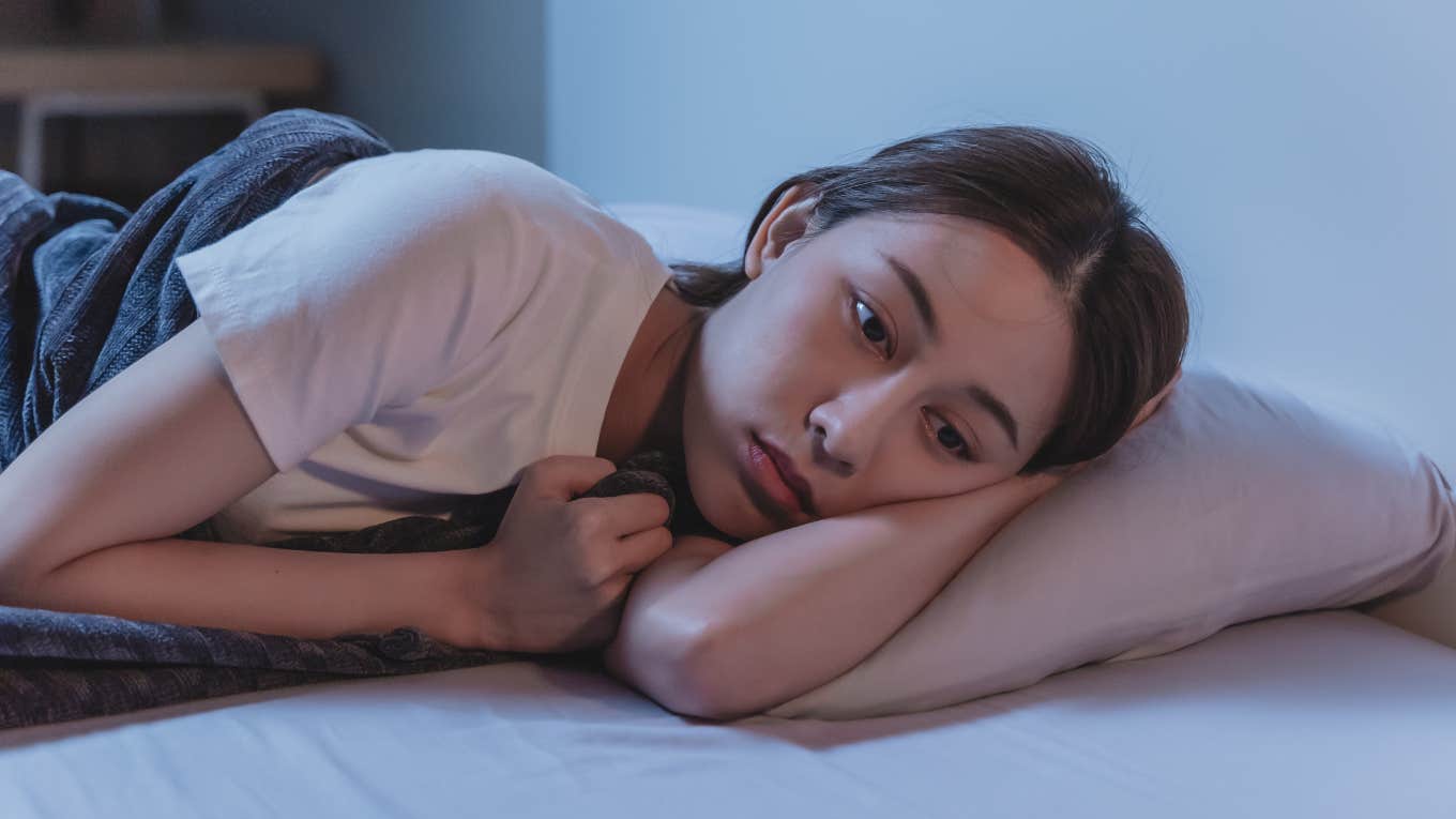 woman lying awake in bed unable to sleep until everything is clean at home