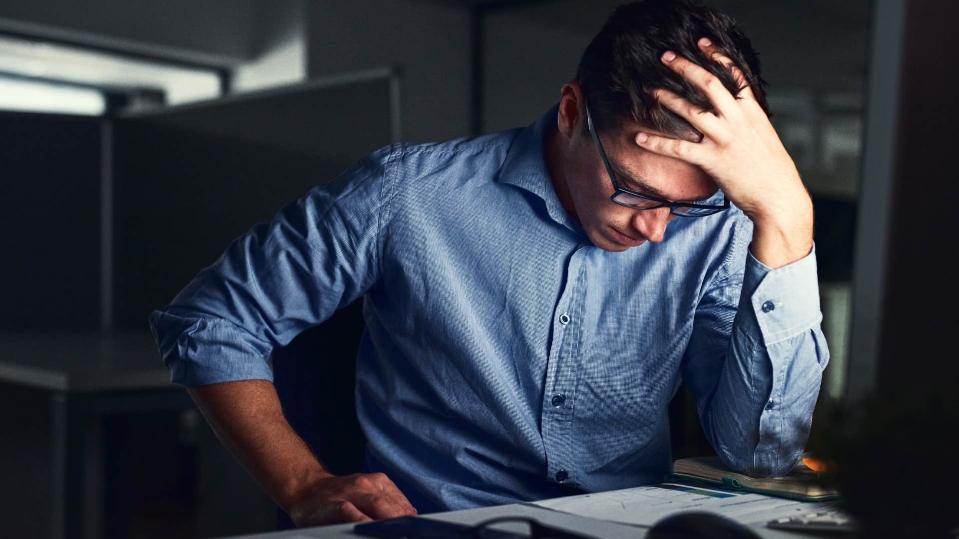 man feeling pressure to overachieve sitting at work