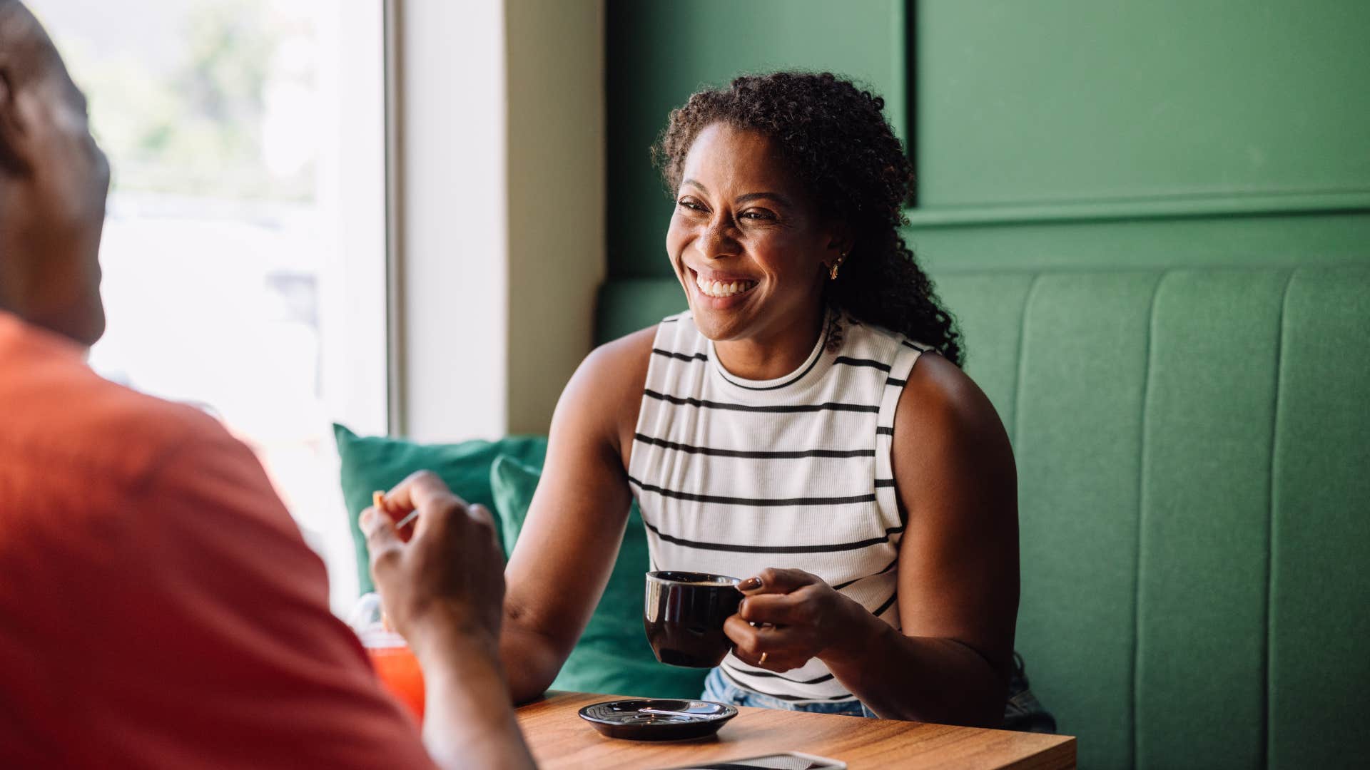 woman smiling at friend while out to eat at restaurant
