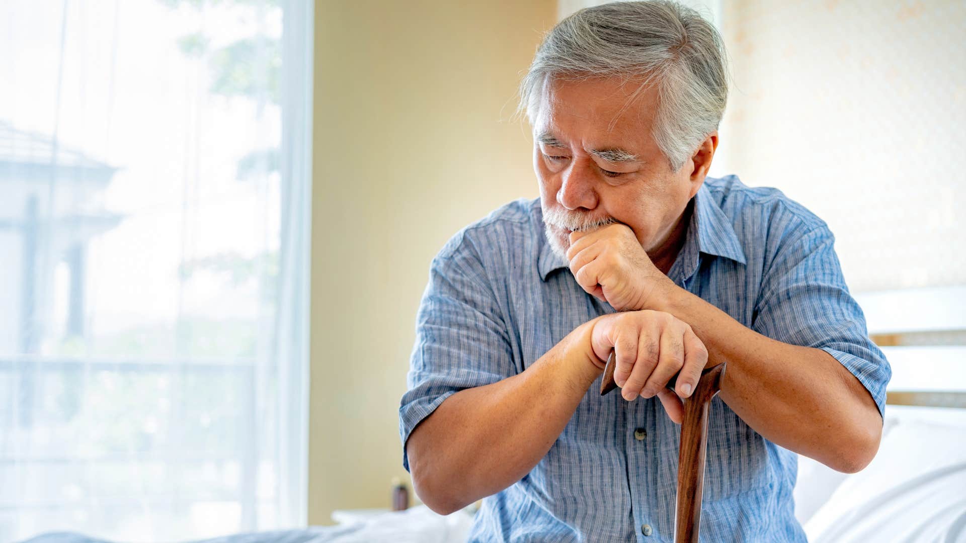 older sad man who feels physically bound to his house sitting with his cane