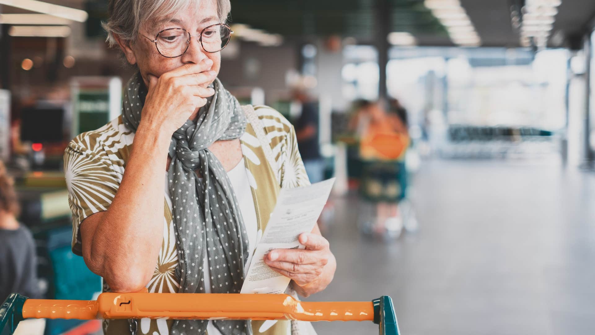 older woman looking at paper receipt in store