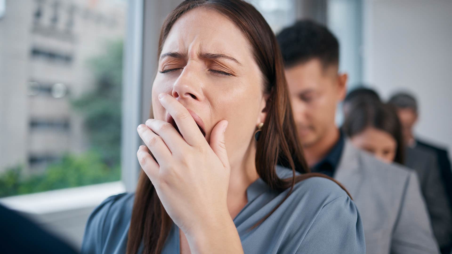 woman yawning while standing in line