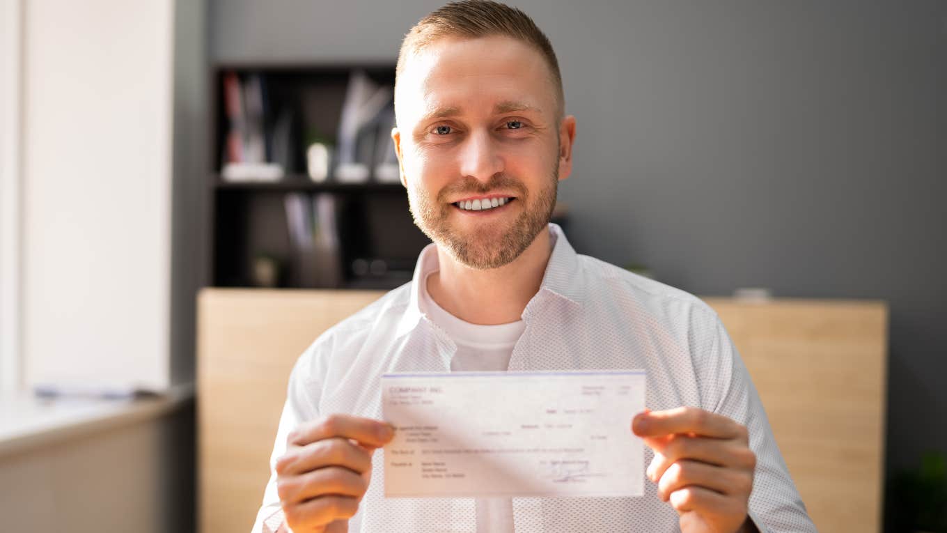 man with old-school principles holding up a check