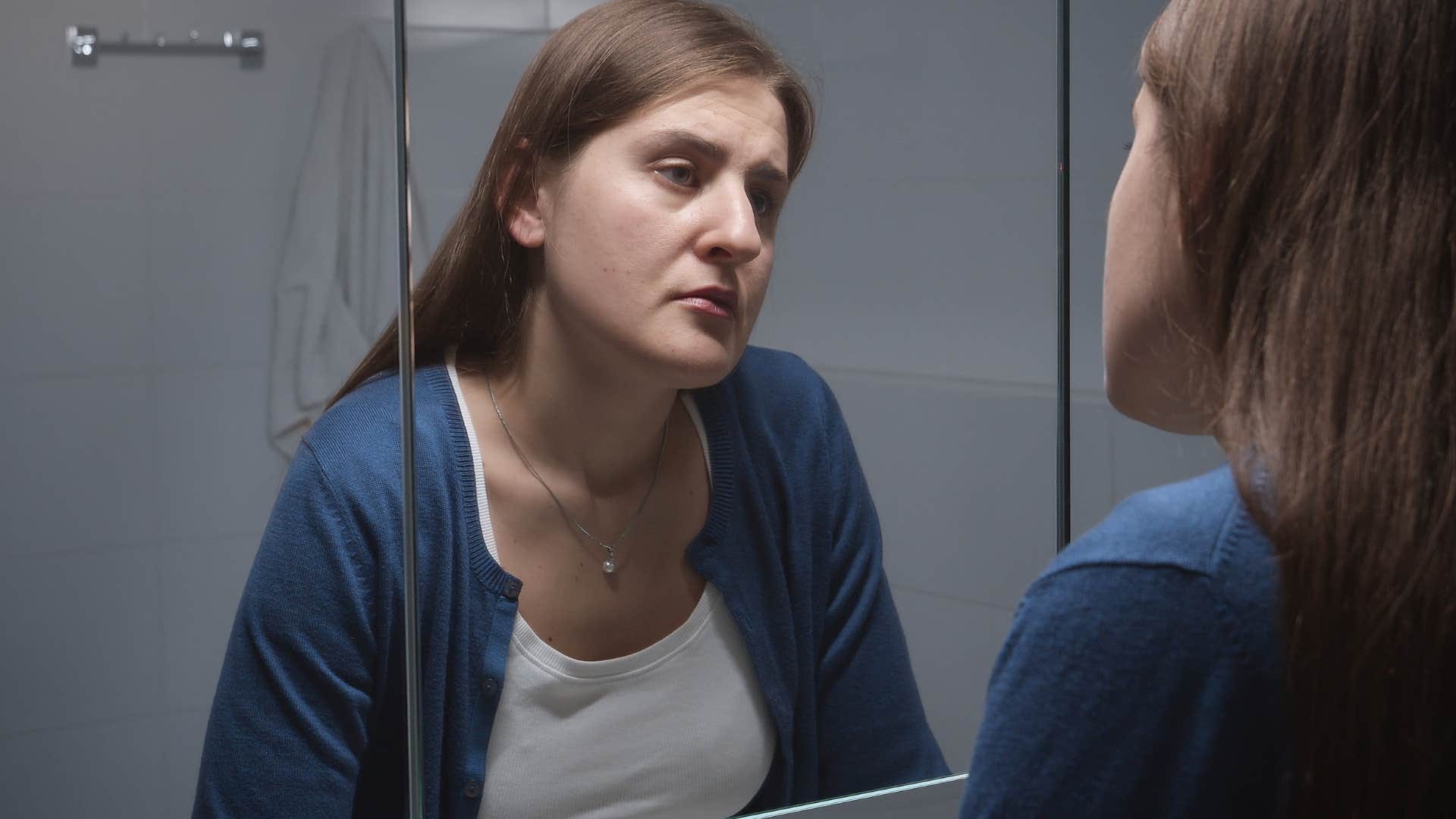 burned out woman looking at herself in the mirror