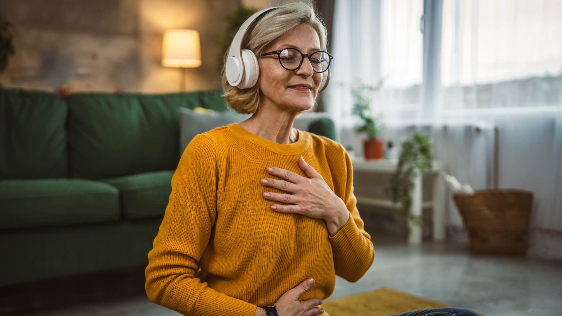 older woman meditating at home with headphones