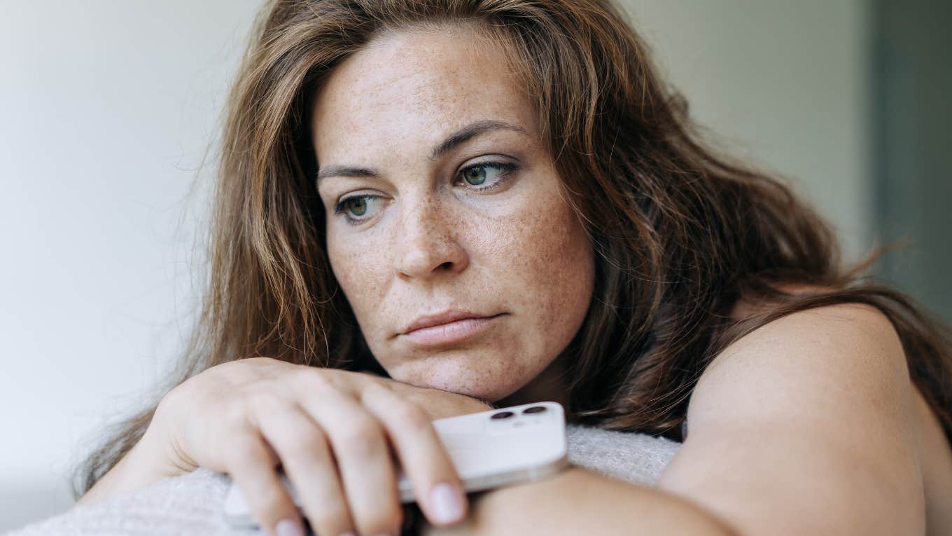 woman holding her phone looking upset