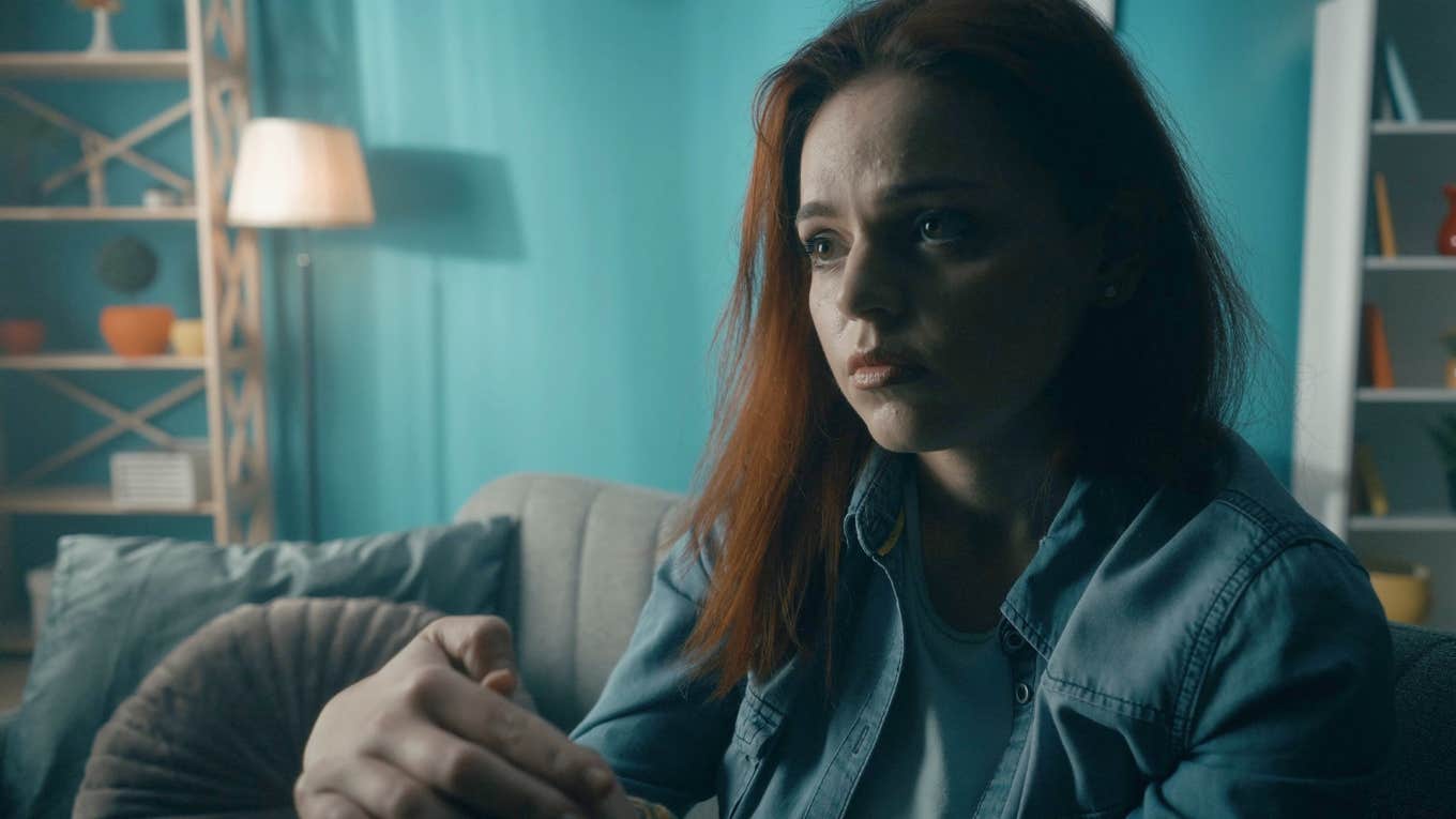 serious woman sitting in dimly lit room thinking