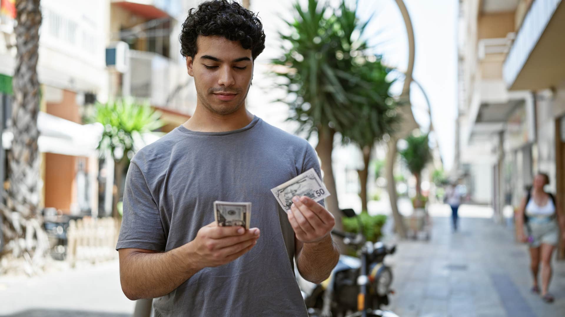 man feeling anxious about finances holding money
