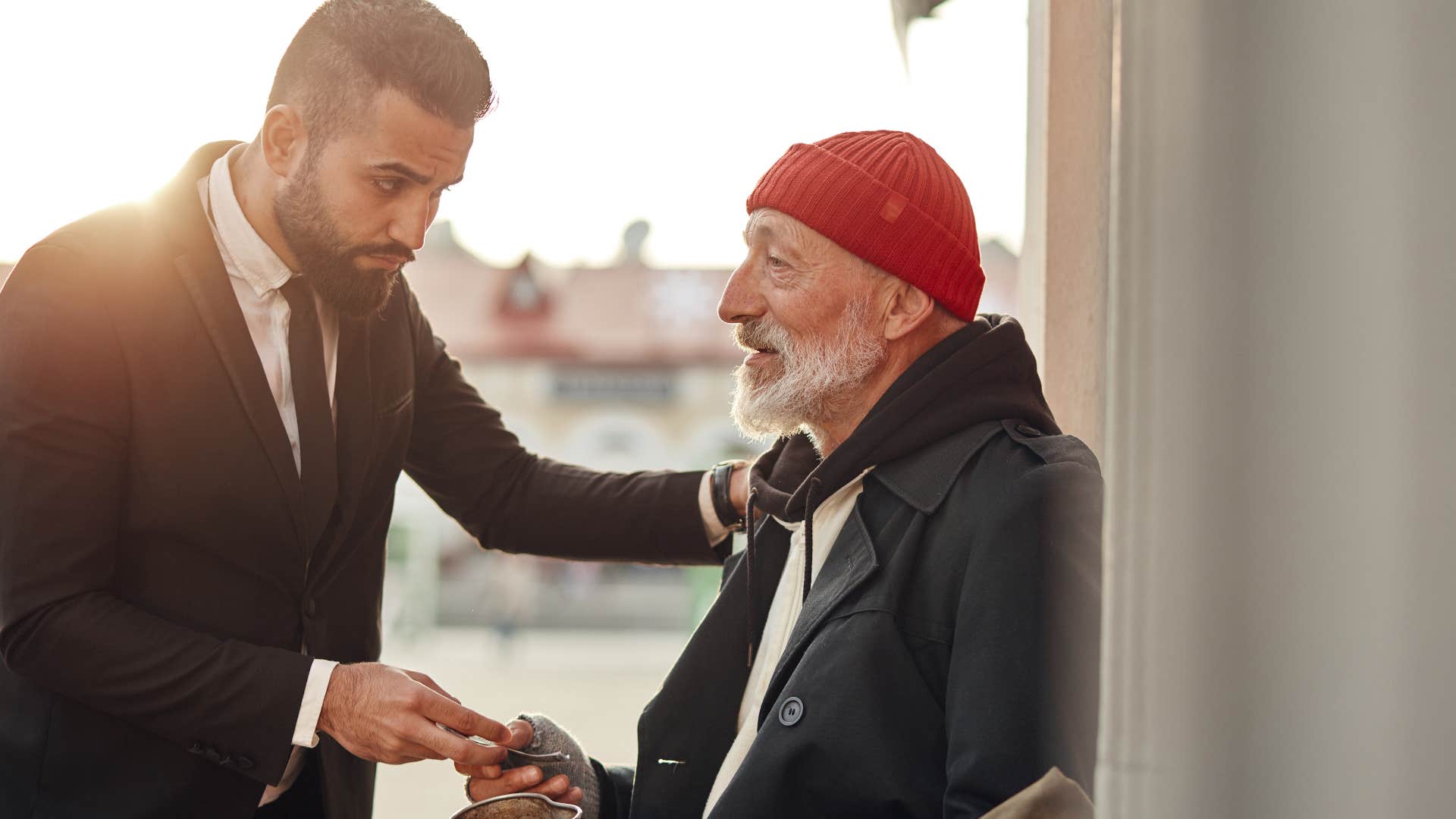 man helping unhoused person being kind