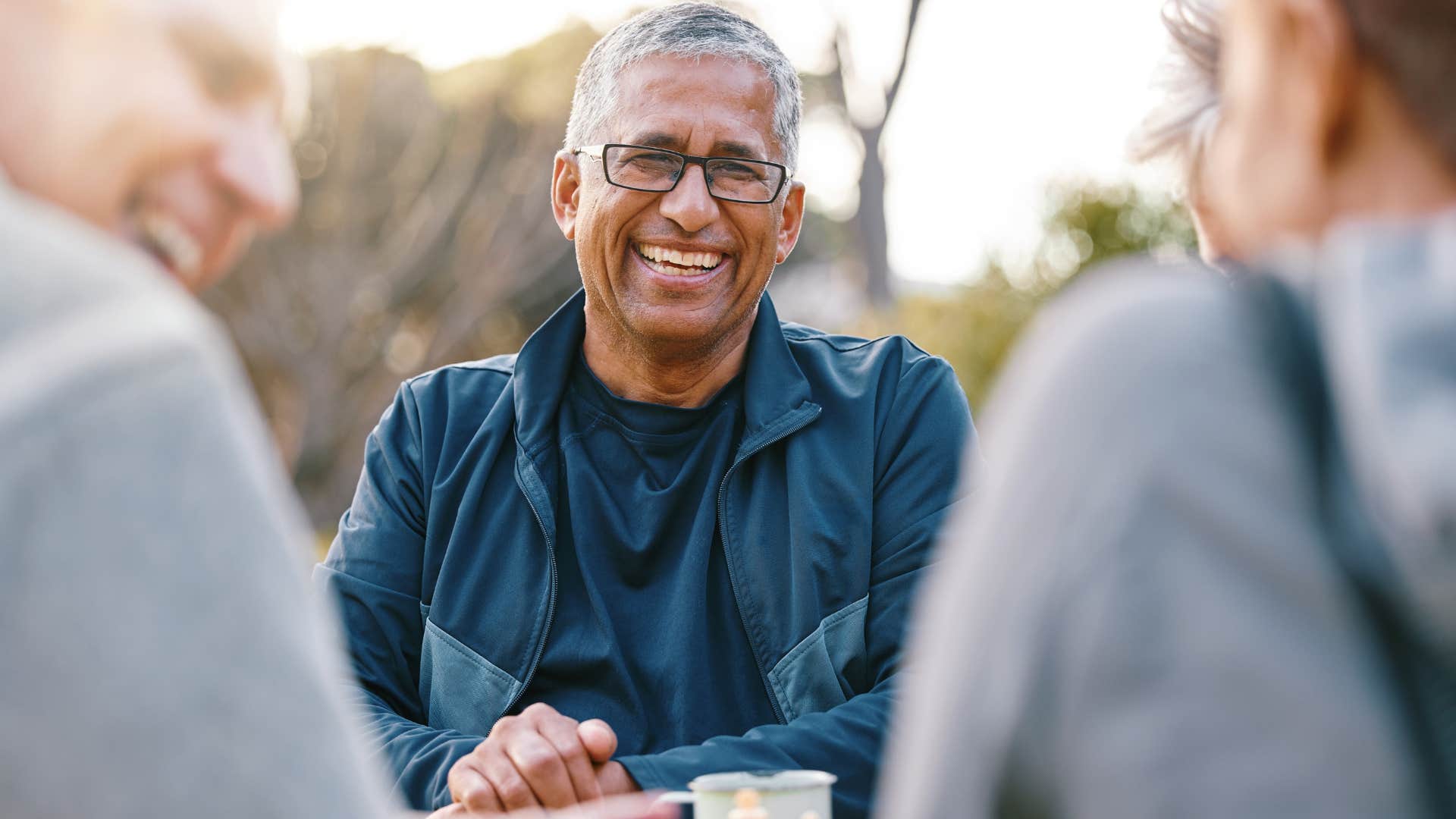 man laughing while talking with friends