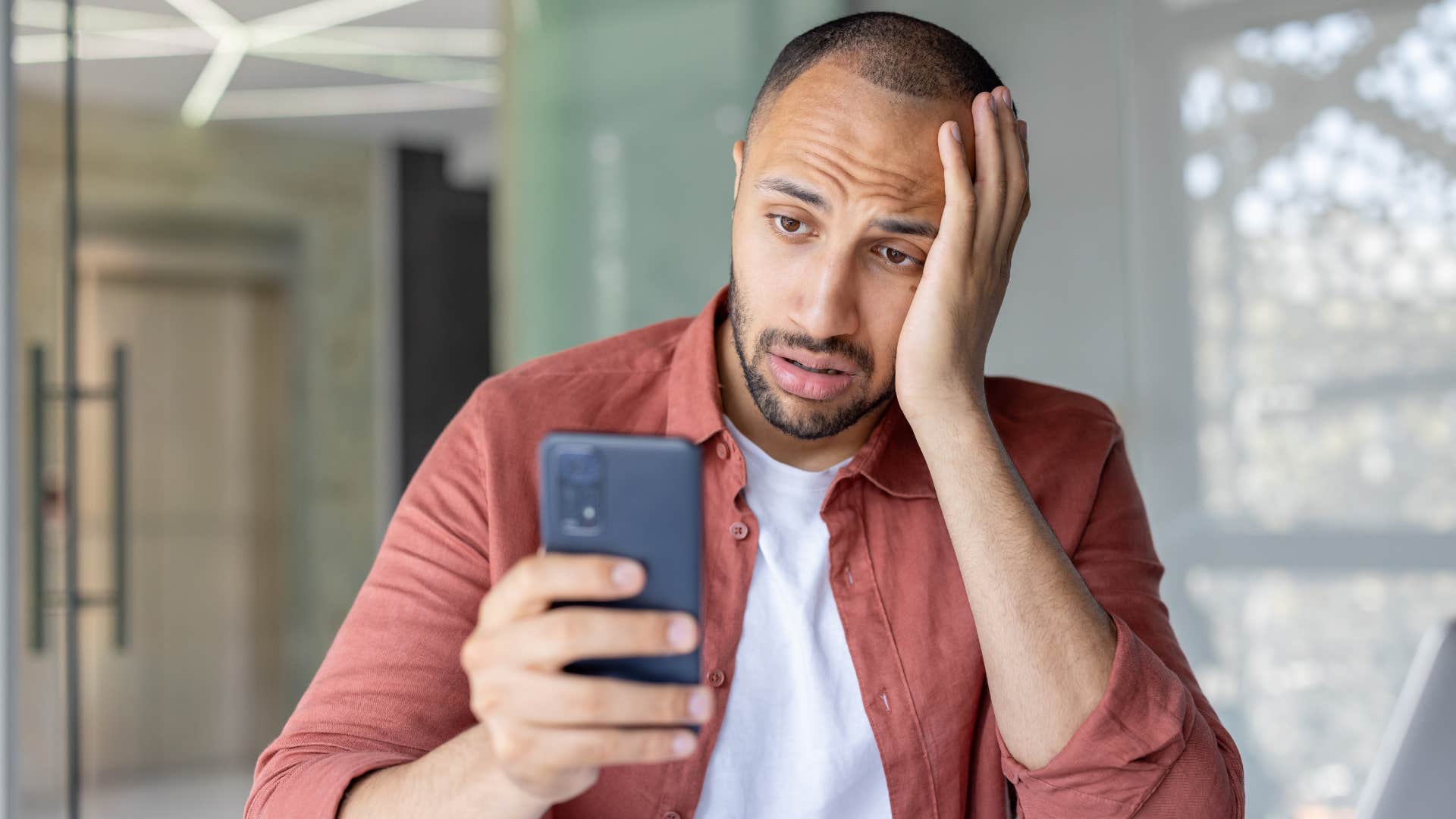 man looking annoyed at phone as he's a victim of fraud