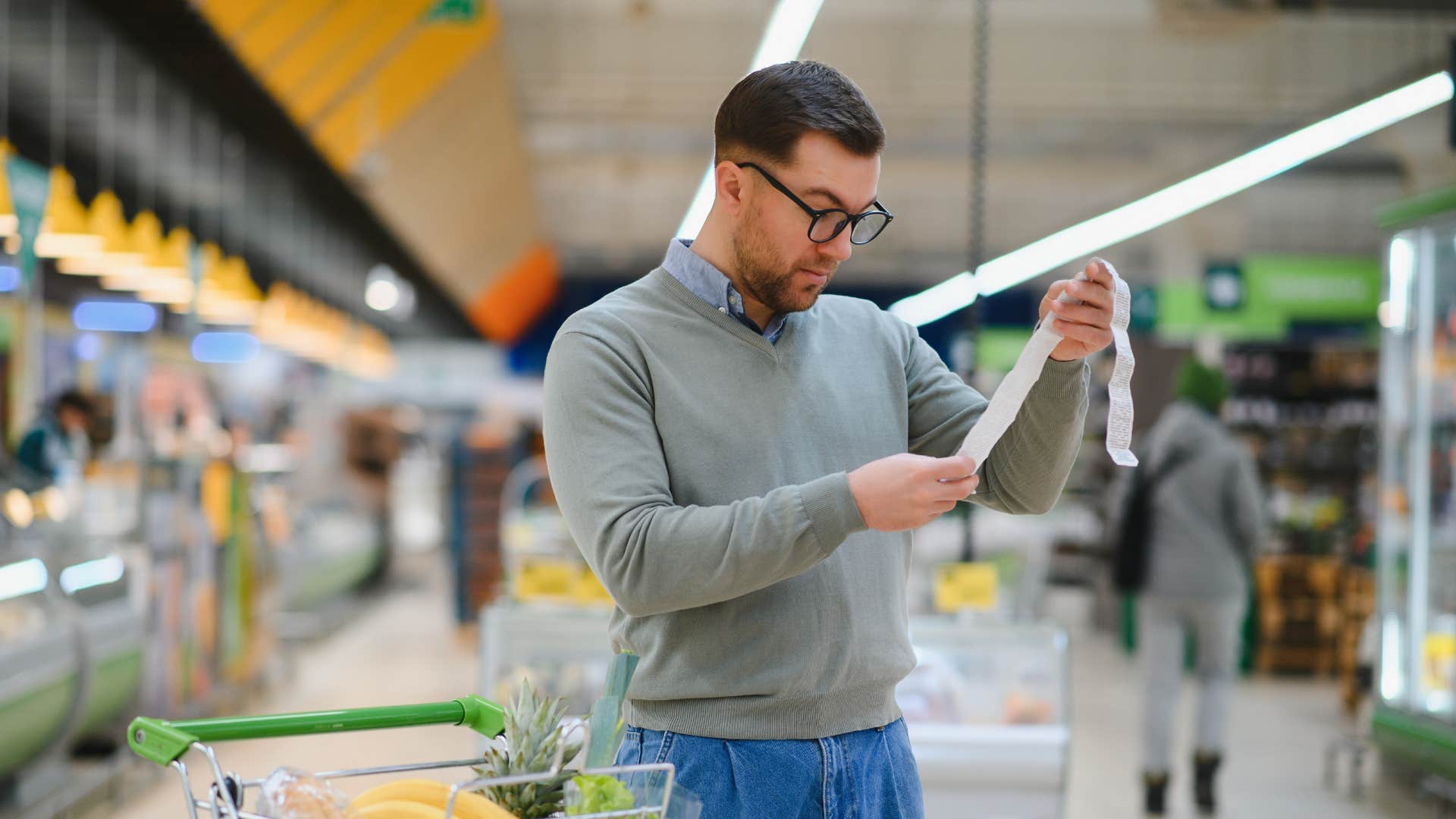 man in gray forgetting what he purchased as he checks receipt 