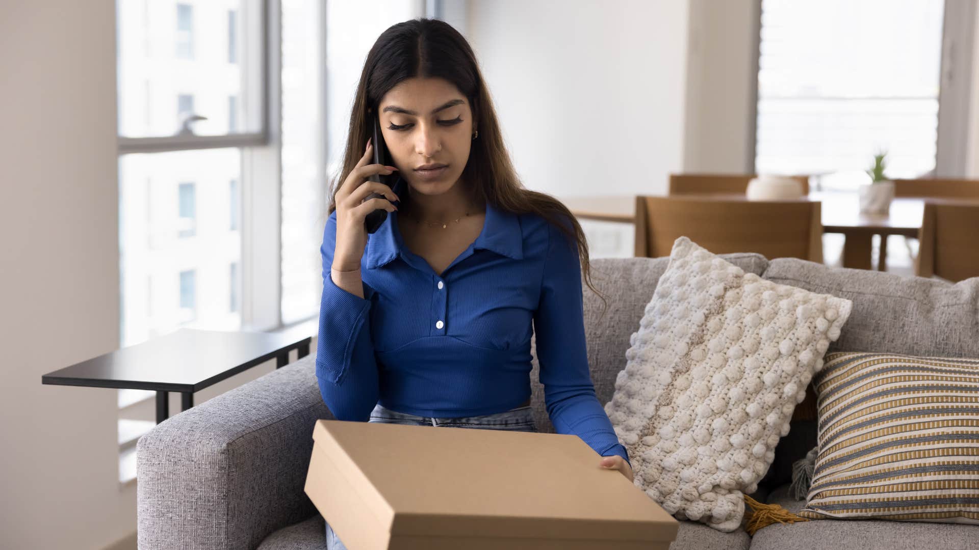 woman in blue shirt on the phone as she needs to return or exchange item