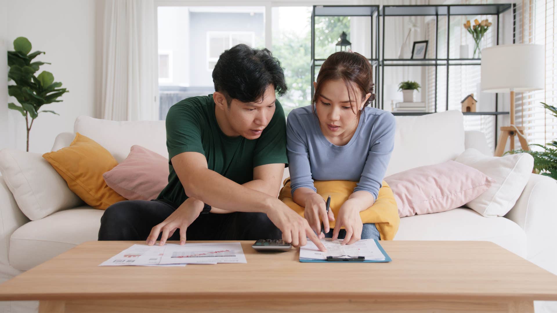 couple sitting on couch as they track family expenses