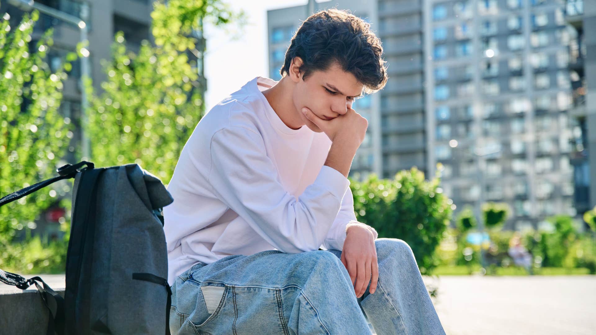 young man sitting outside feeling alone