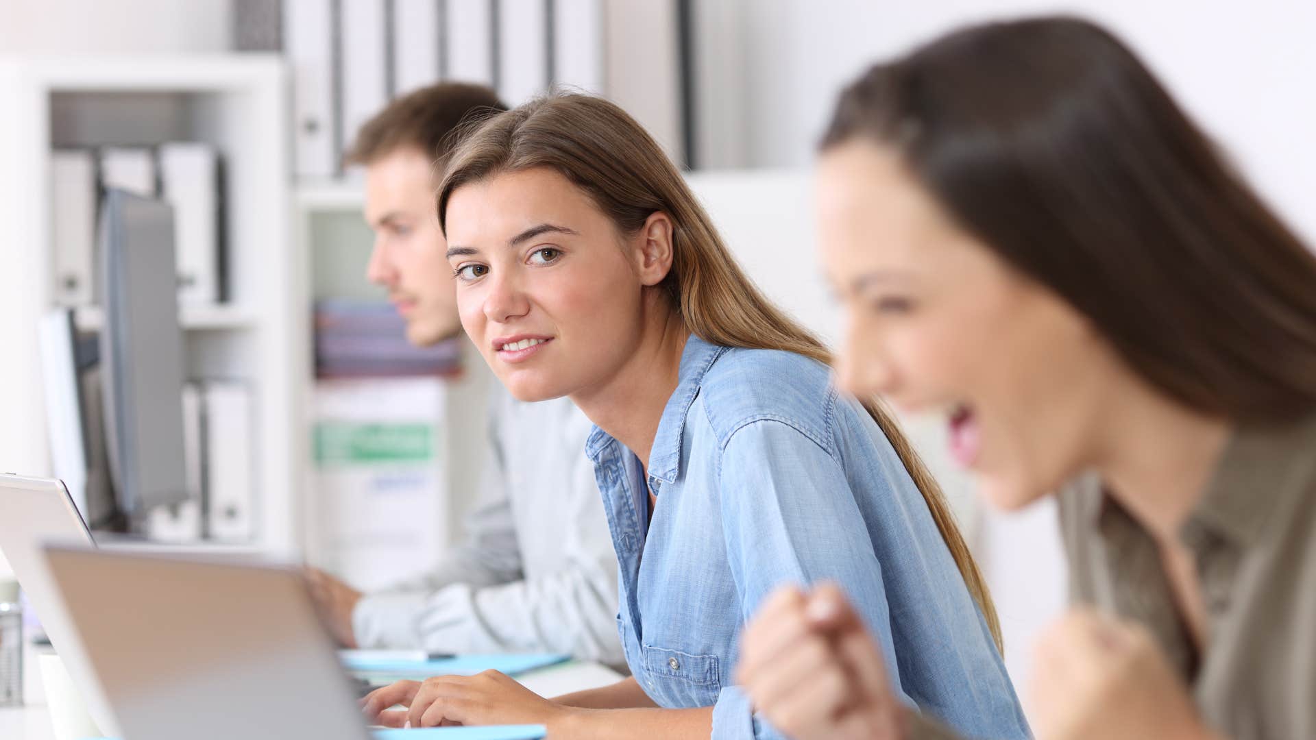 annoyed woman watching co-worker succeed