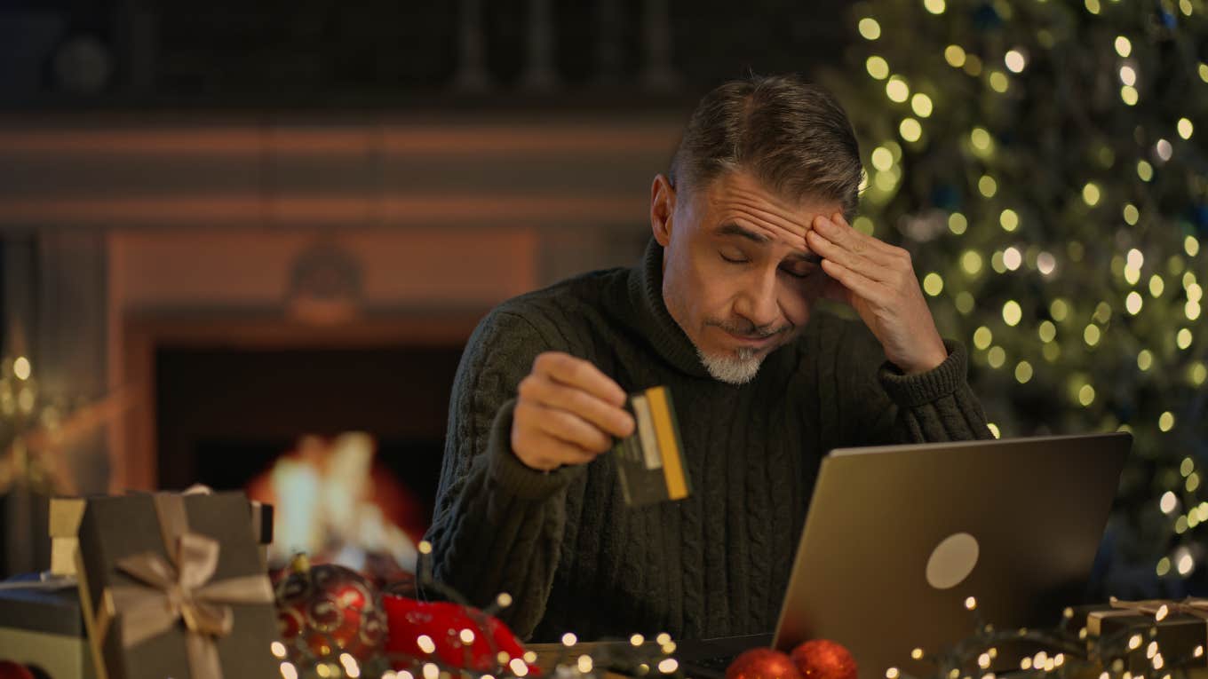 stressed man buying gifts for the holidays on his laptop holding credit card